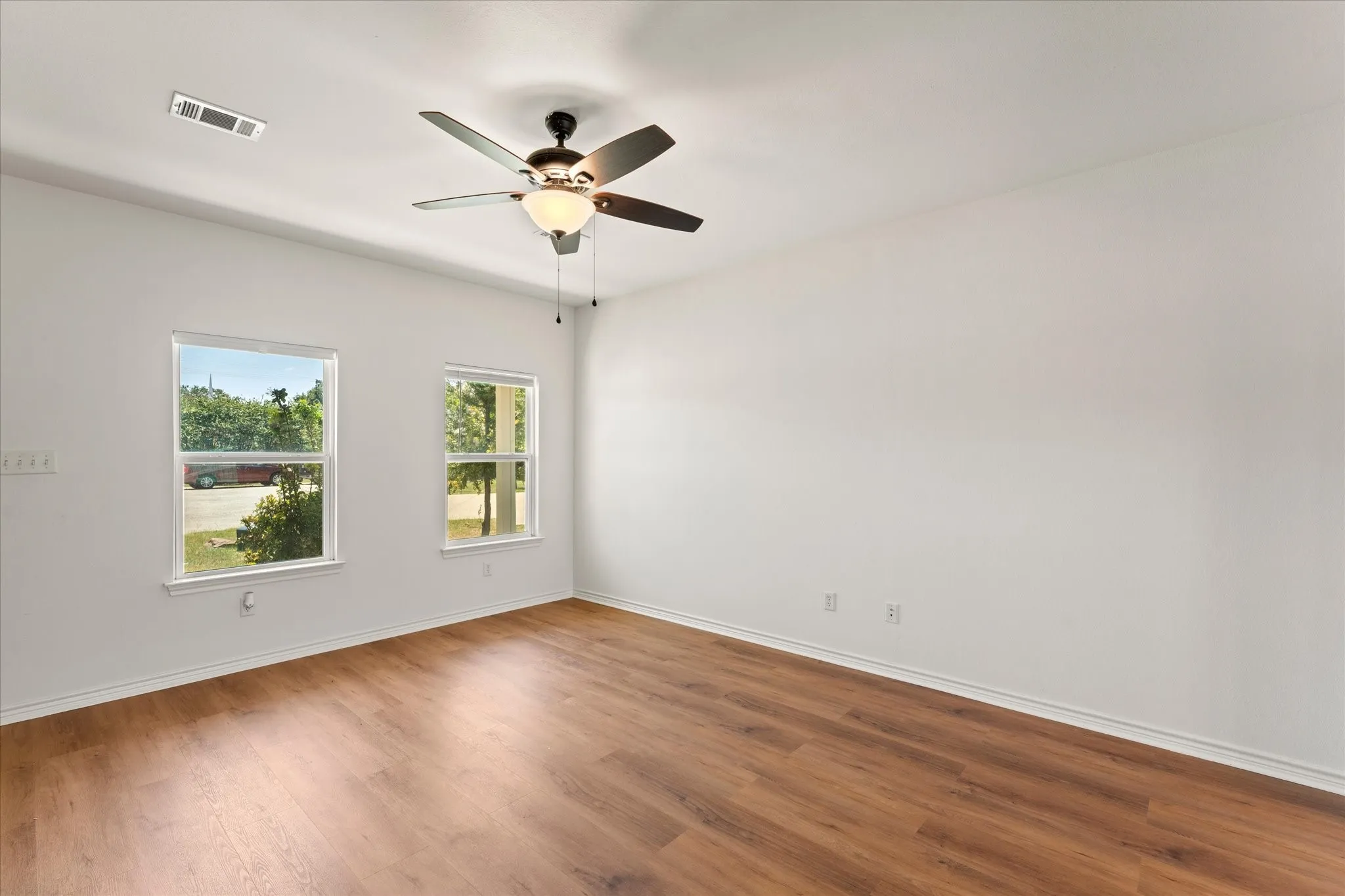Wood-finish flooring, dual windows, and a ceiling fan with integrated lighting