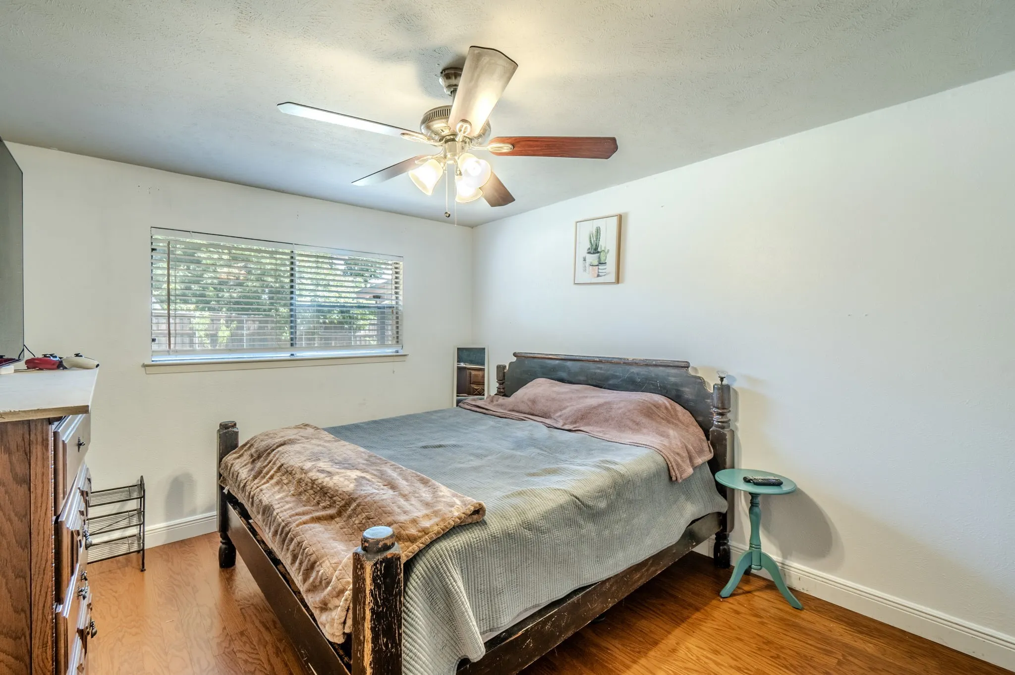 Hardwood-style flooring, ceiling fan with integrated lighting, and a large window with blinds