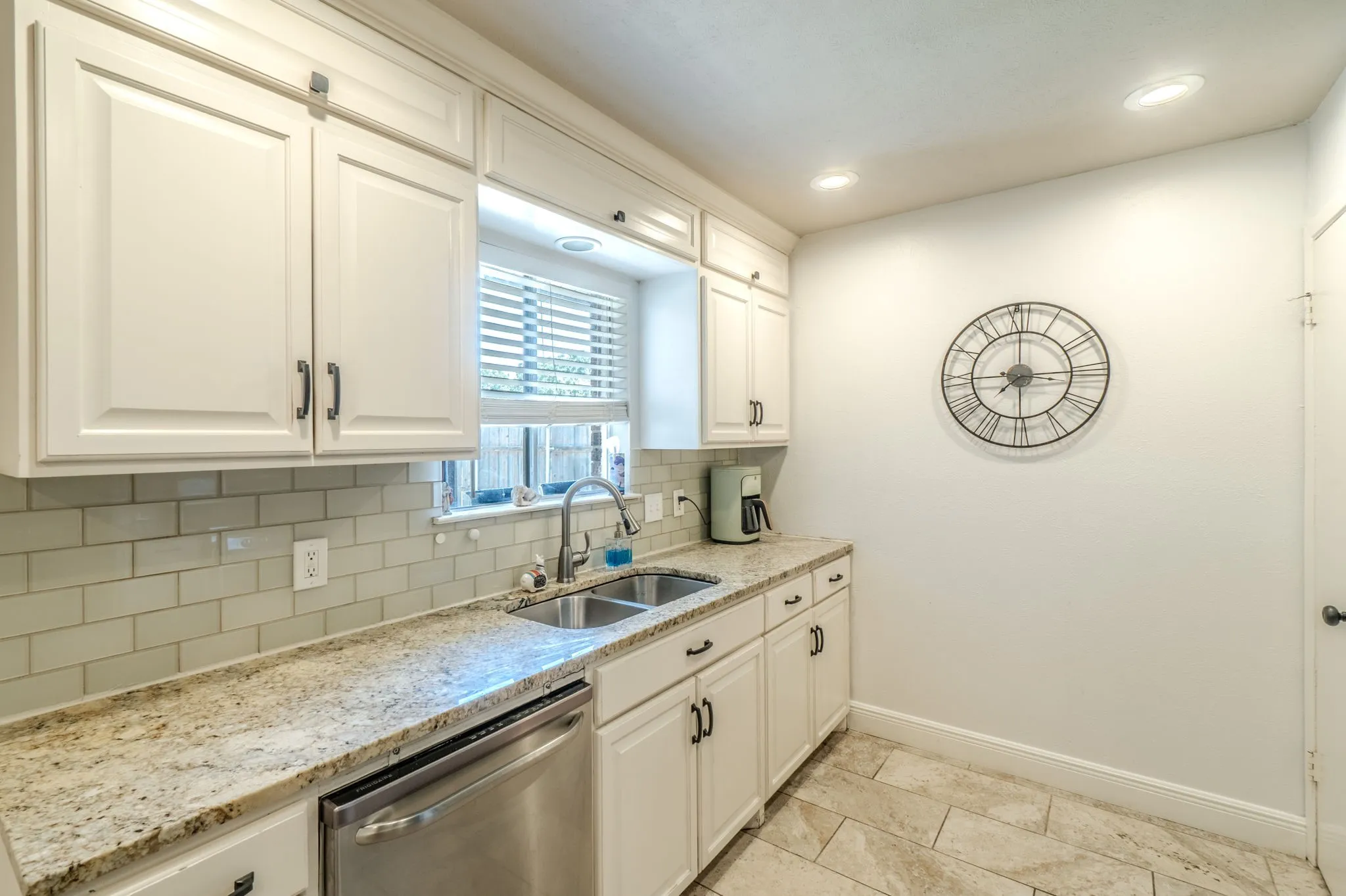 White cabinetry with dark hardware, stone countertops, stainless steel dishwasher, subway tile backsplash, and recessed lighting