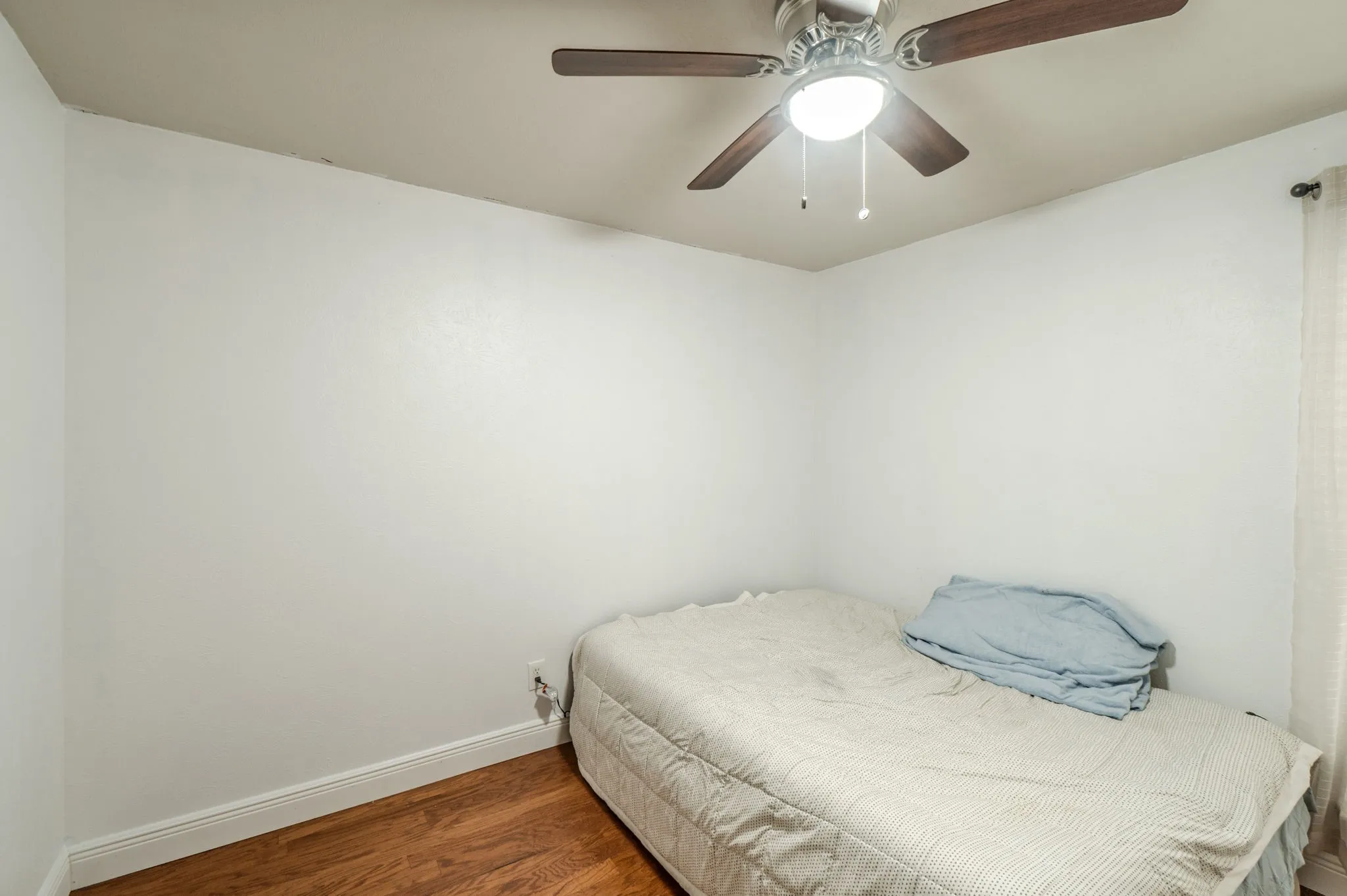 Wood-finish flooring, ceiling fan with integrated lighting, and white wall finishes
