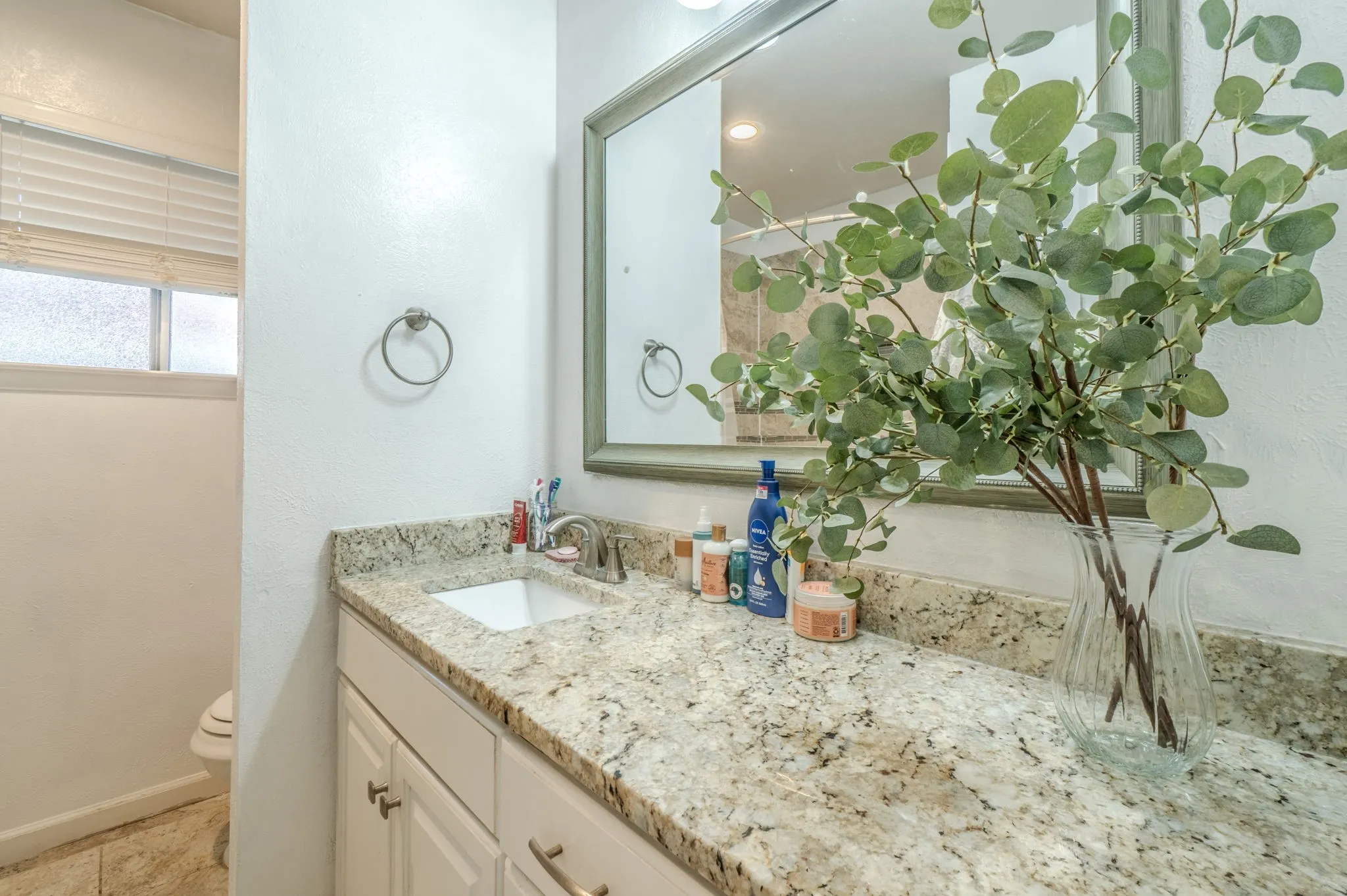 Vanity with a light-toned countertop, an undermount sink, and a framed mirror