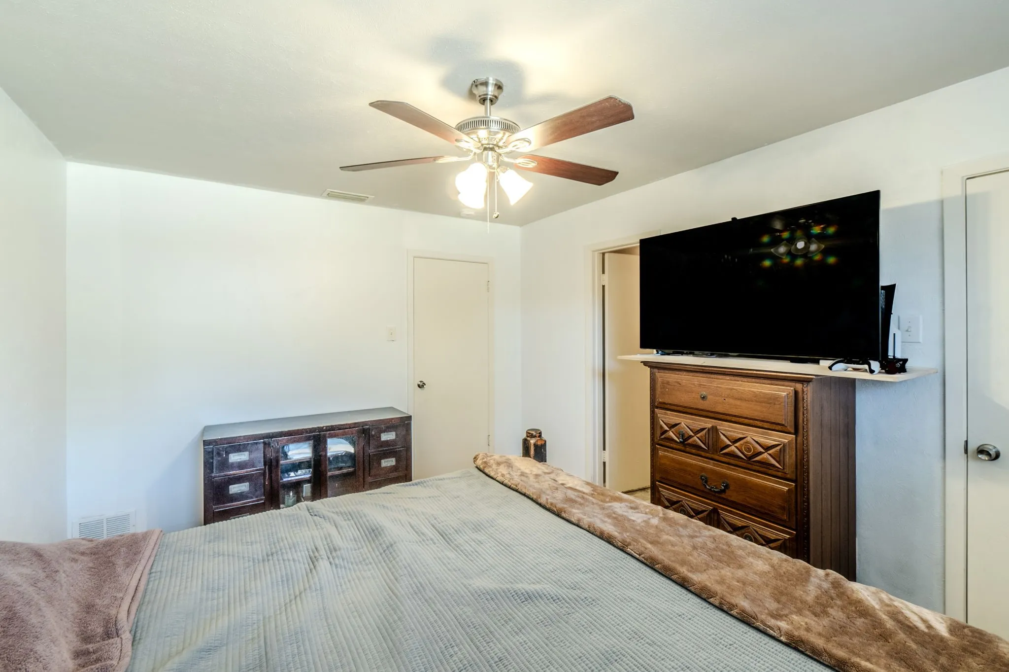 White walls with a ceiling fan featuring wood-finish blades and integrated lighting