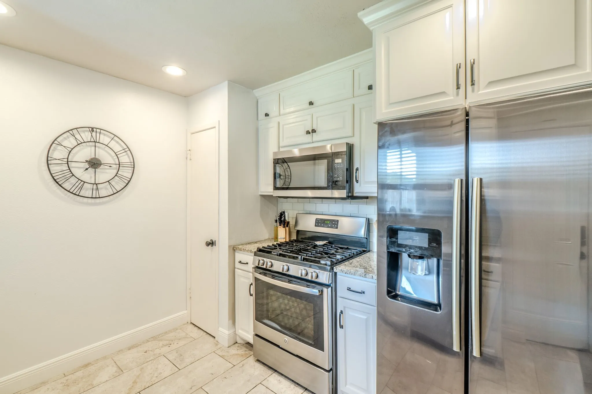 Kitchen featuring stainless steel appliances, white cabinetry, granite countertops, and recessed lighting
