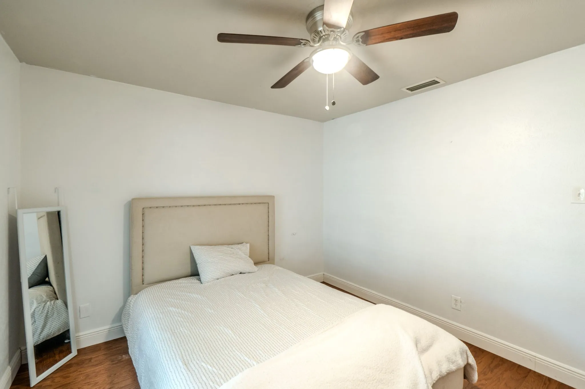 Wood-finish flooring, ceiling fan with integrated lighting, and a white wall finish