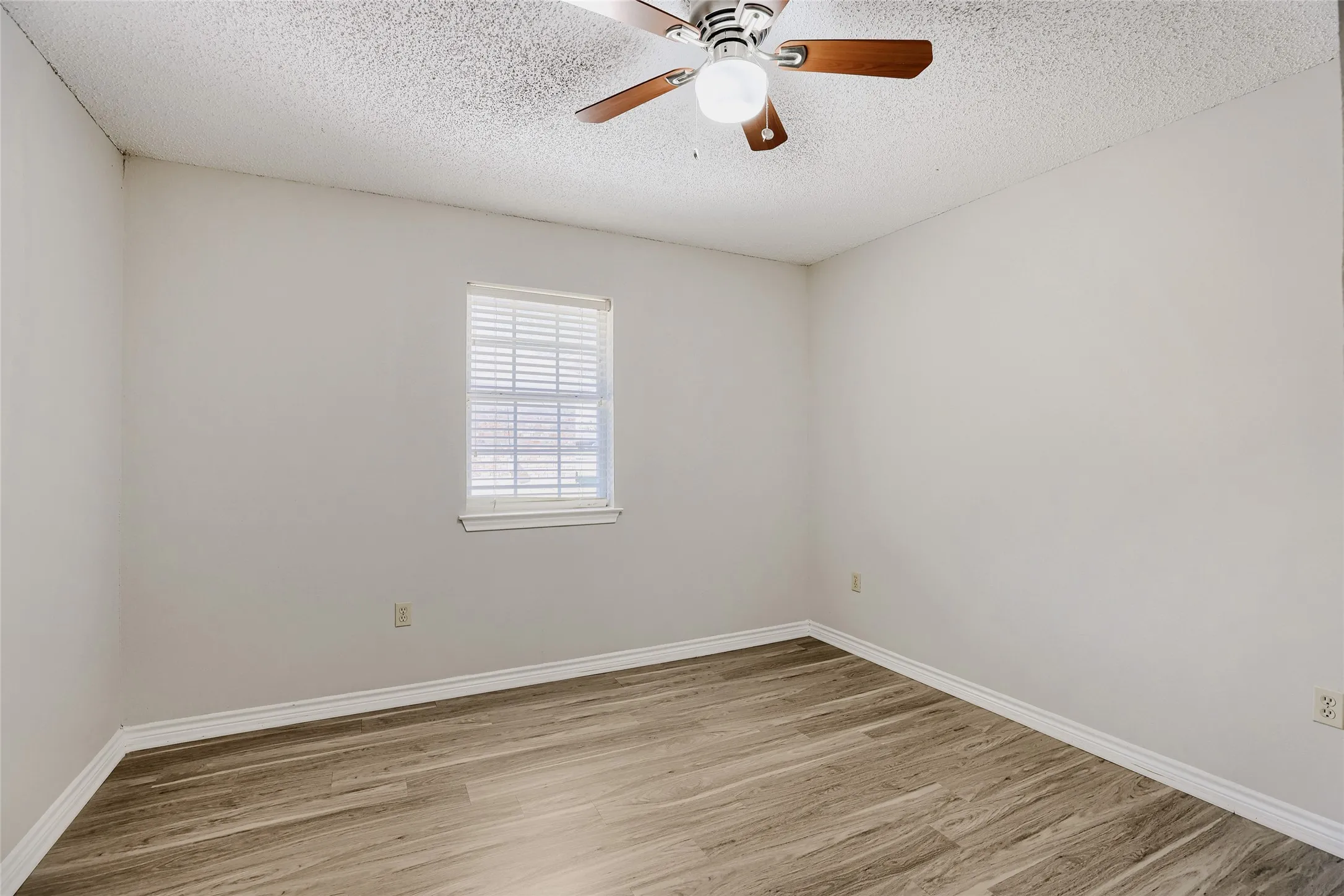 Wood-finish flooring, single window, white window blinds, and a ceiling fan with integrated lighting