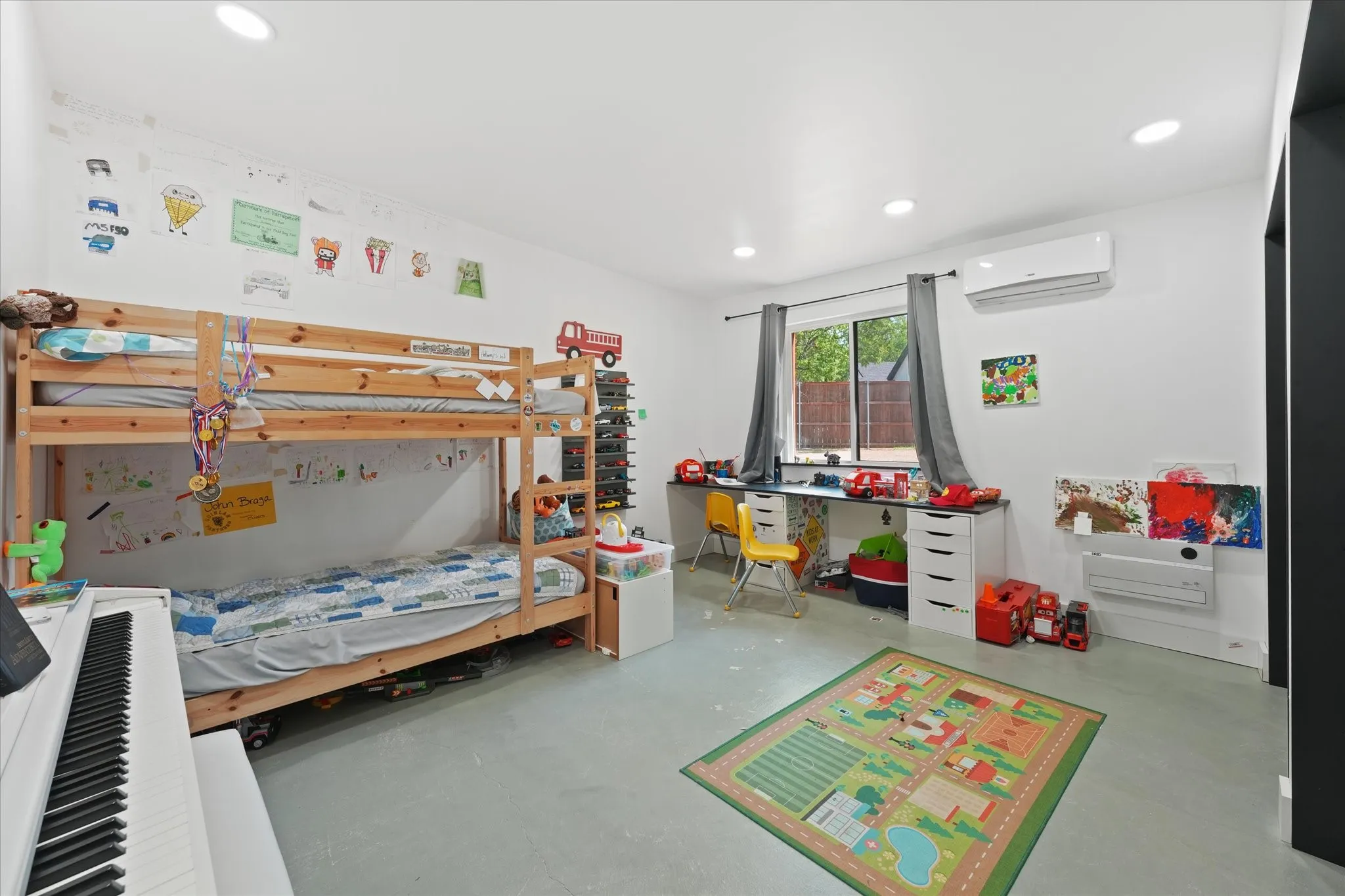 Bright, light-filled bedroom featuring polished concrete flooring, wooden bunk bed frame with integrated storage, recessed ceiling lighting, split-unit air conditioning, and large windows with natural light