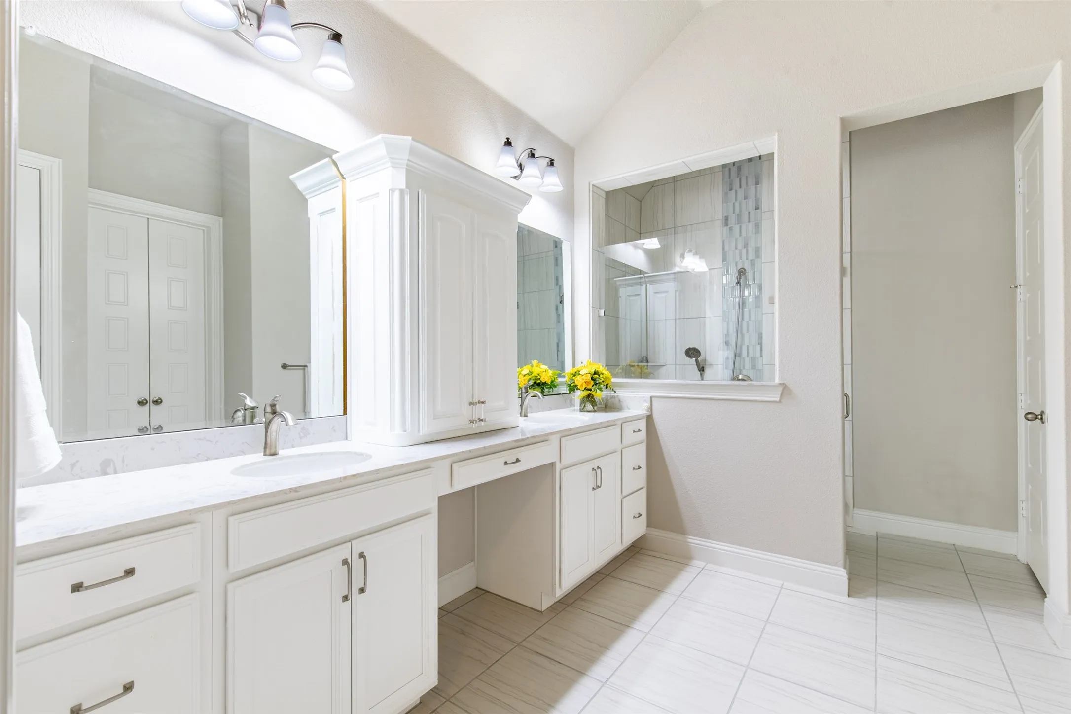 This is a really large primary bathroom. Love the dual sinks with the cabinet separating the space.