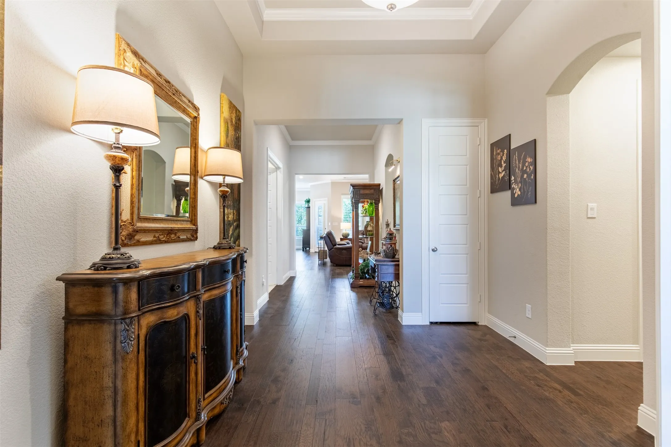 What a stunning foyer with gleaming wood flooring! On the right, is a hallway that goes to the utility room, mudroom, and garage entrance as well as a powder bath.