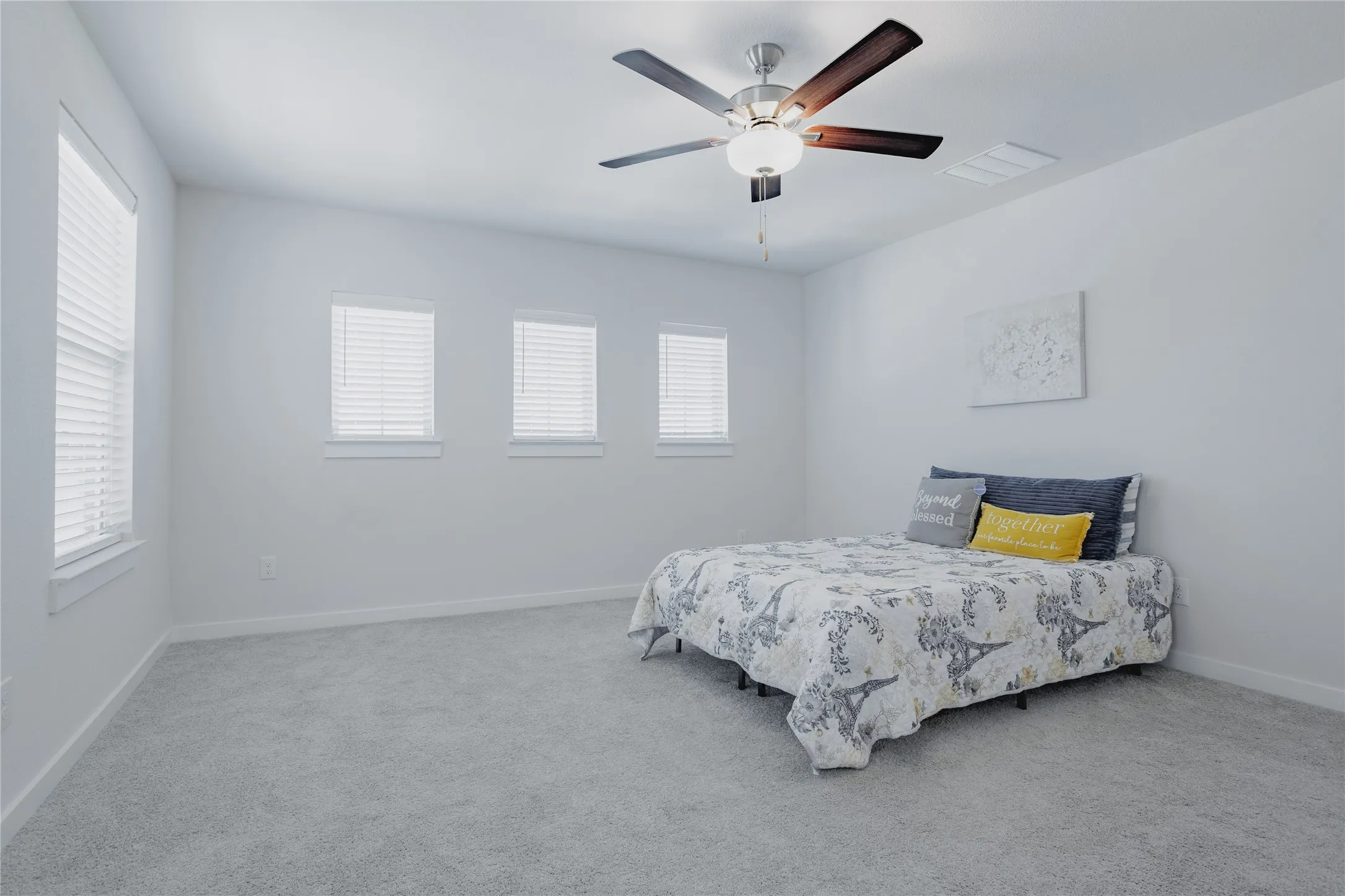Carpeted room featuring multiple windows with blinds and a ceiling fan with light fixture