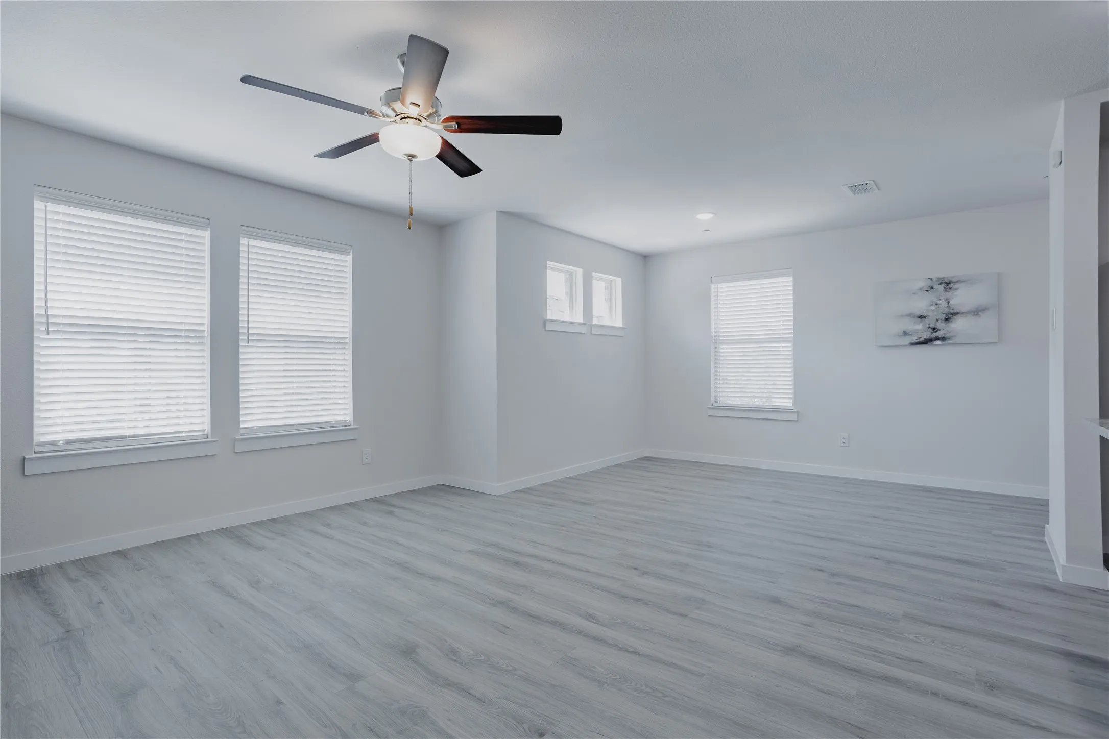 Spacious room featuring wood-finish flooring, multiple windows with blinds, recessed lighting, and a ceiling fan