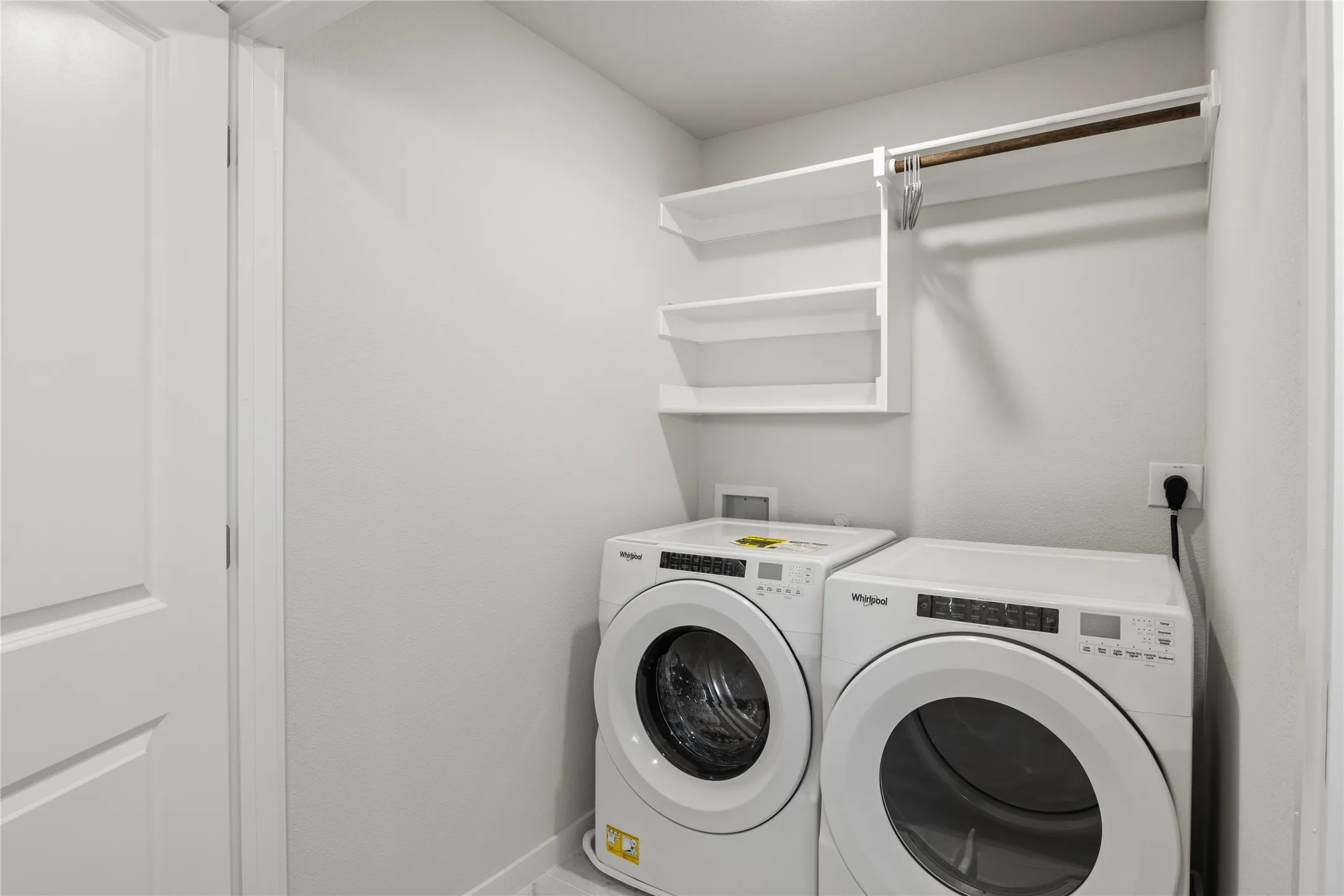Dedicated laundry area featuring built-in shelving, and a hanging rod