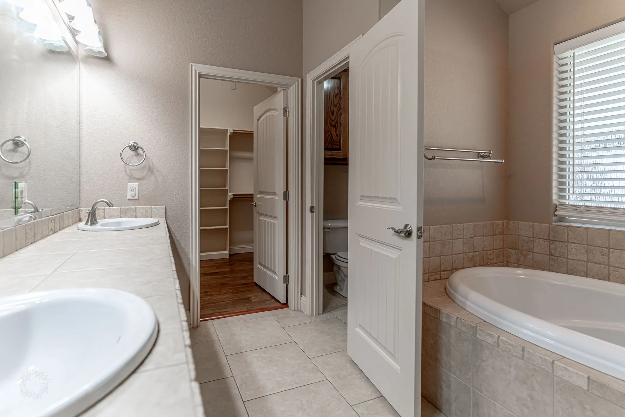 Tiled primary bath with large walk in closet, separate shower, large garden tub and dual vanities