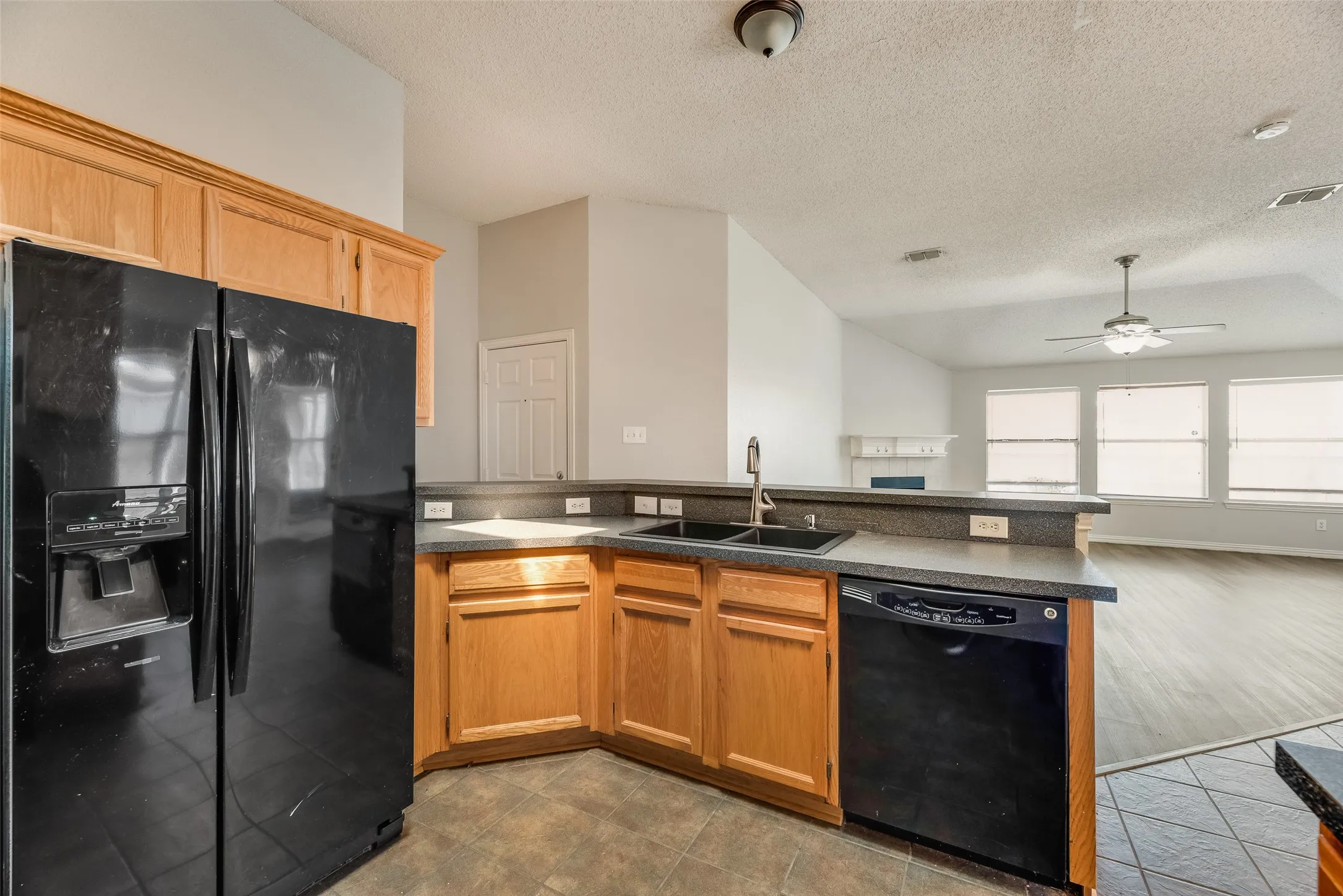 Kitchen featuring wood cabinetry, a dual basin sink, and a black dishwasher
