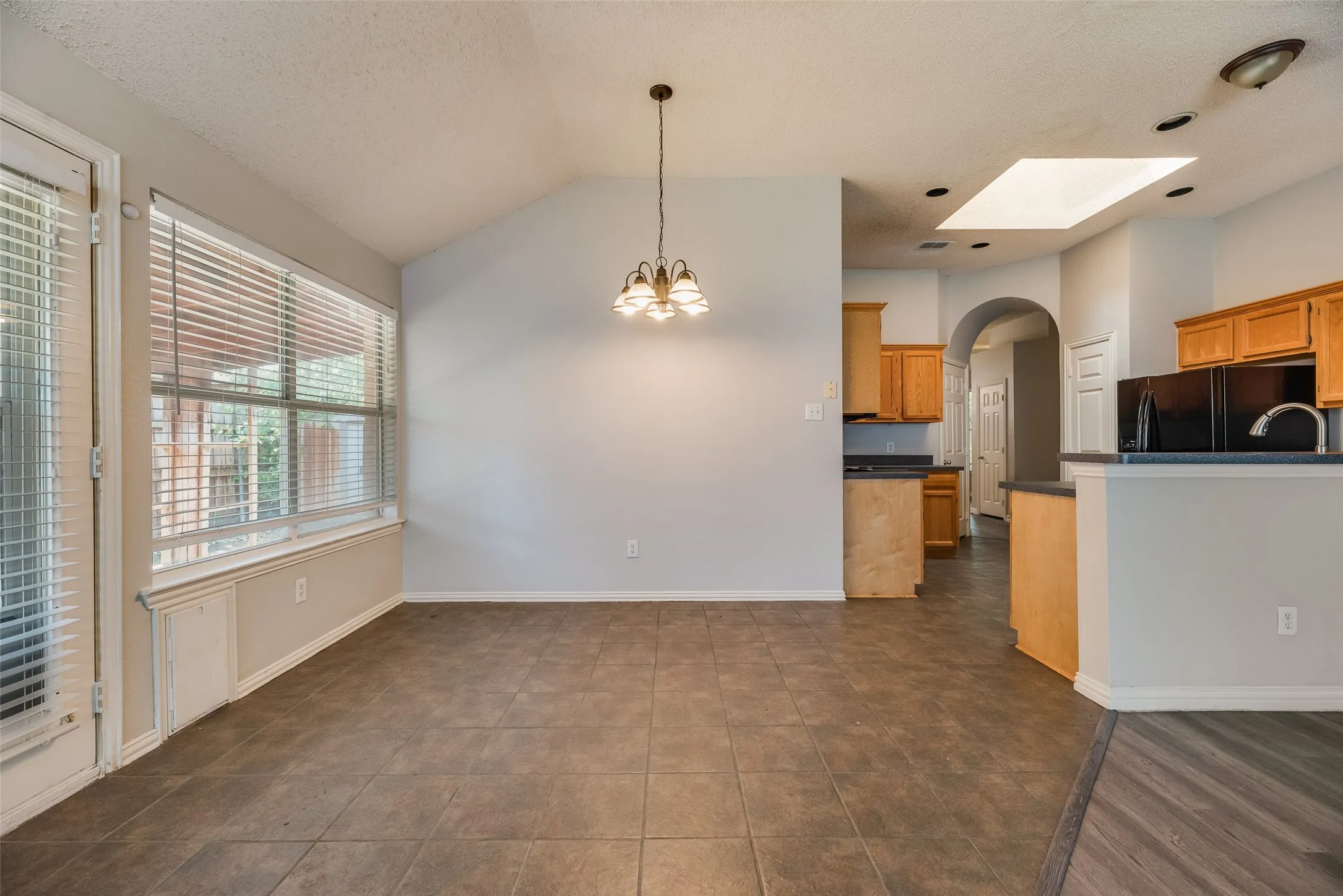 Vaulted ceiling, tile flooring, window with blinds, recessed lighting, and a skylight