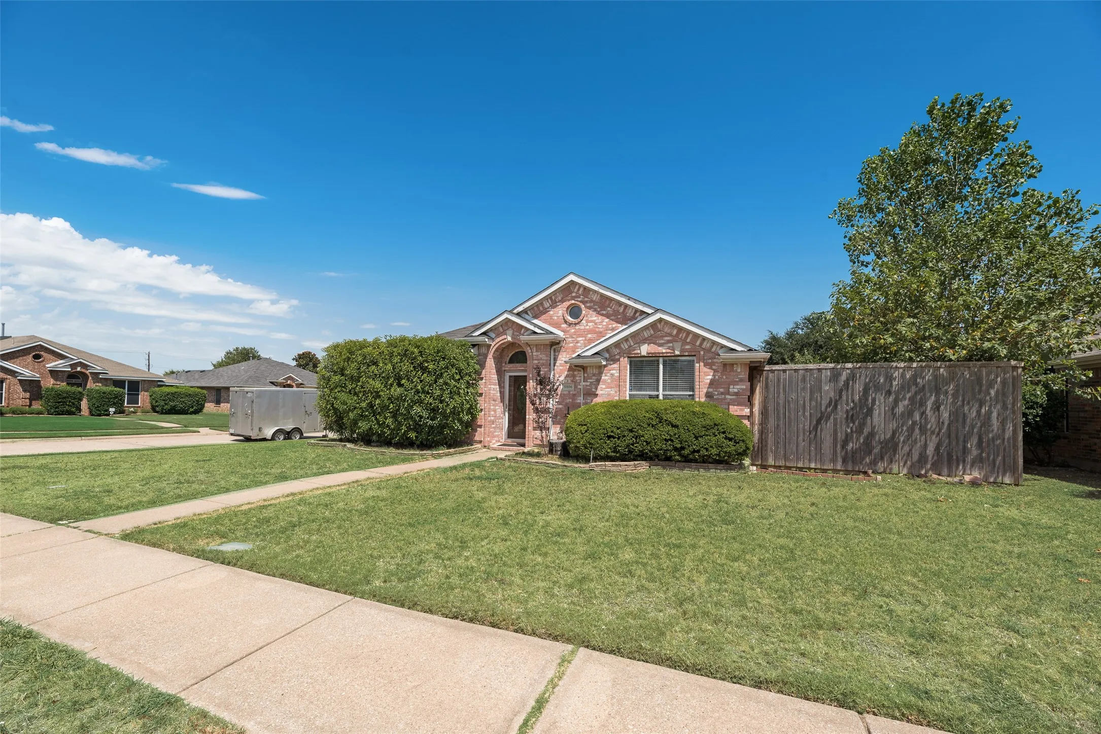 Brick exterior with archway entry, established landscaping, and a side privacy fence