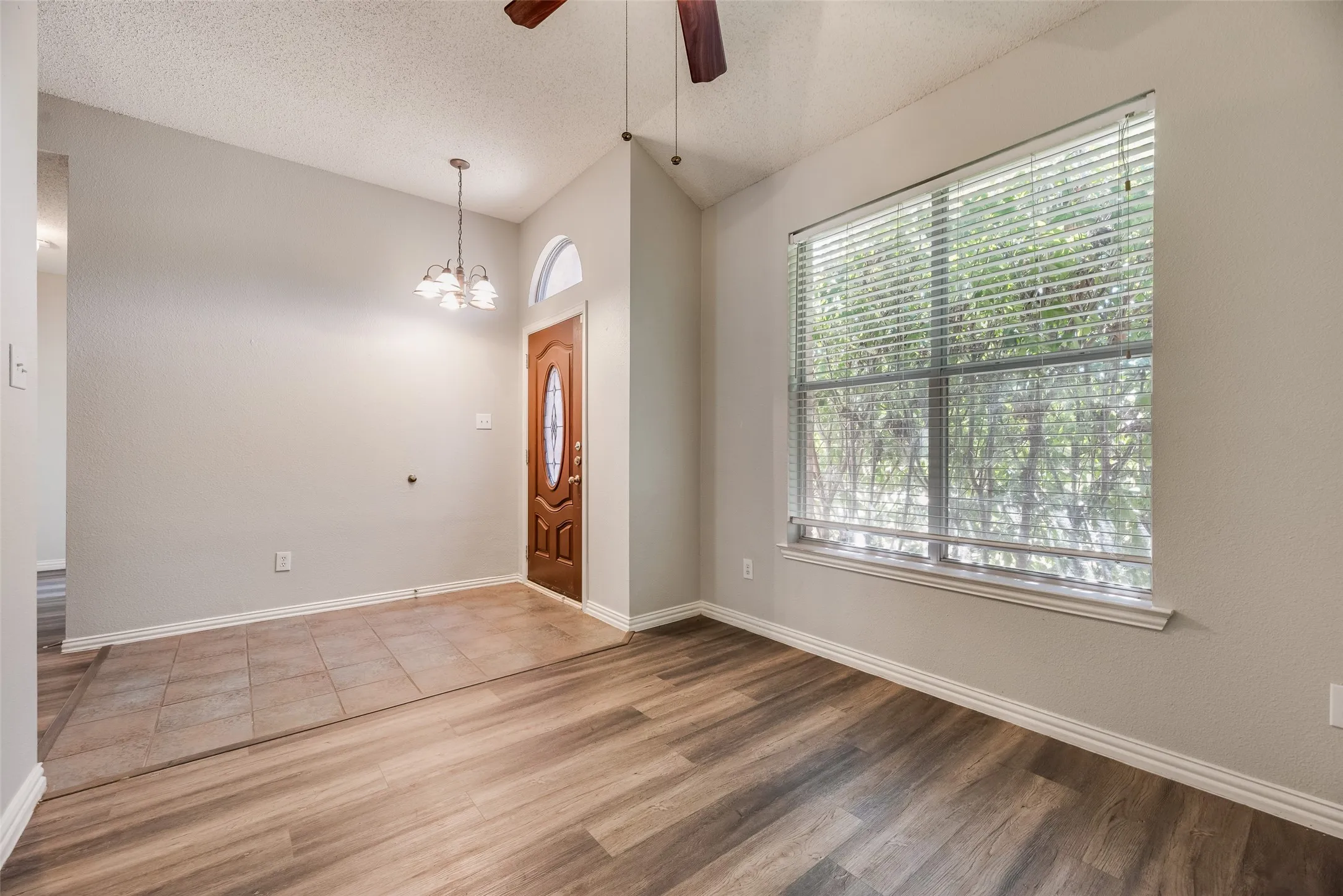 Angled ceiling with a ceiling fan, wood-finish flooring, and a large window