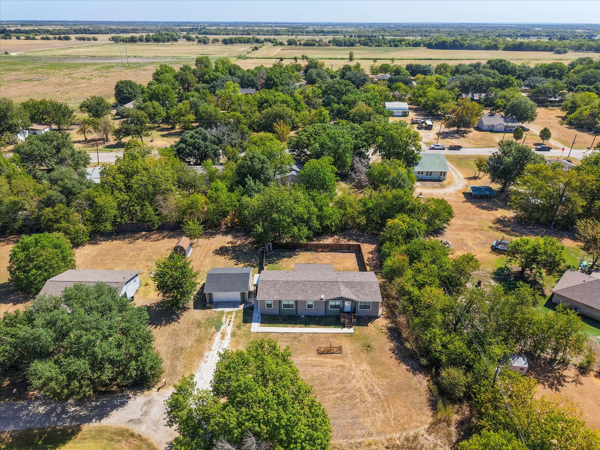 Elevated property view showcasing the Kerens TX home, detached garage, spacious lot and surrounding Navarro County neighborhood.