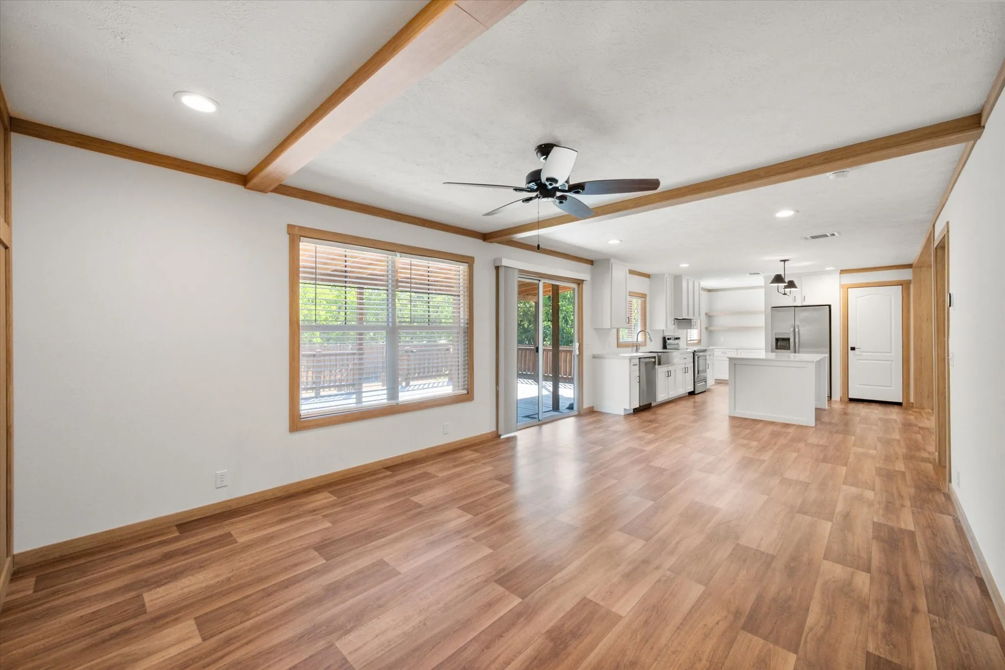 Kitchen view highlights the oversized island, stainless steel appliances, white cabinetry and open flow into the home's living spaces.