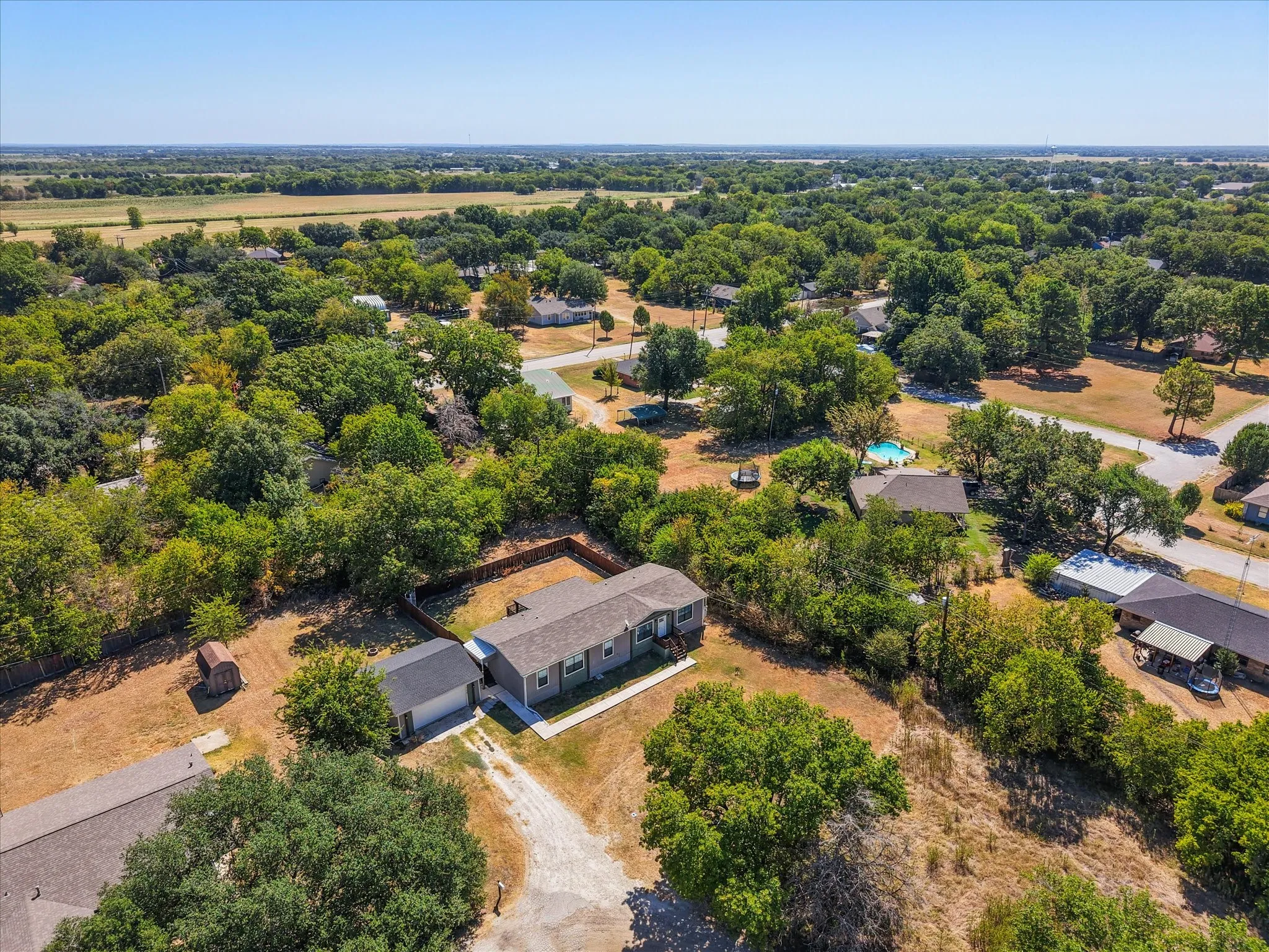 Elevated neighborhood view shows 716 N Wright Avenue surrounded by established homes, mature trees and open Navarro County countryside.