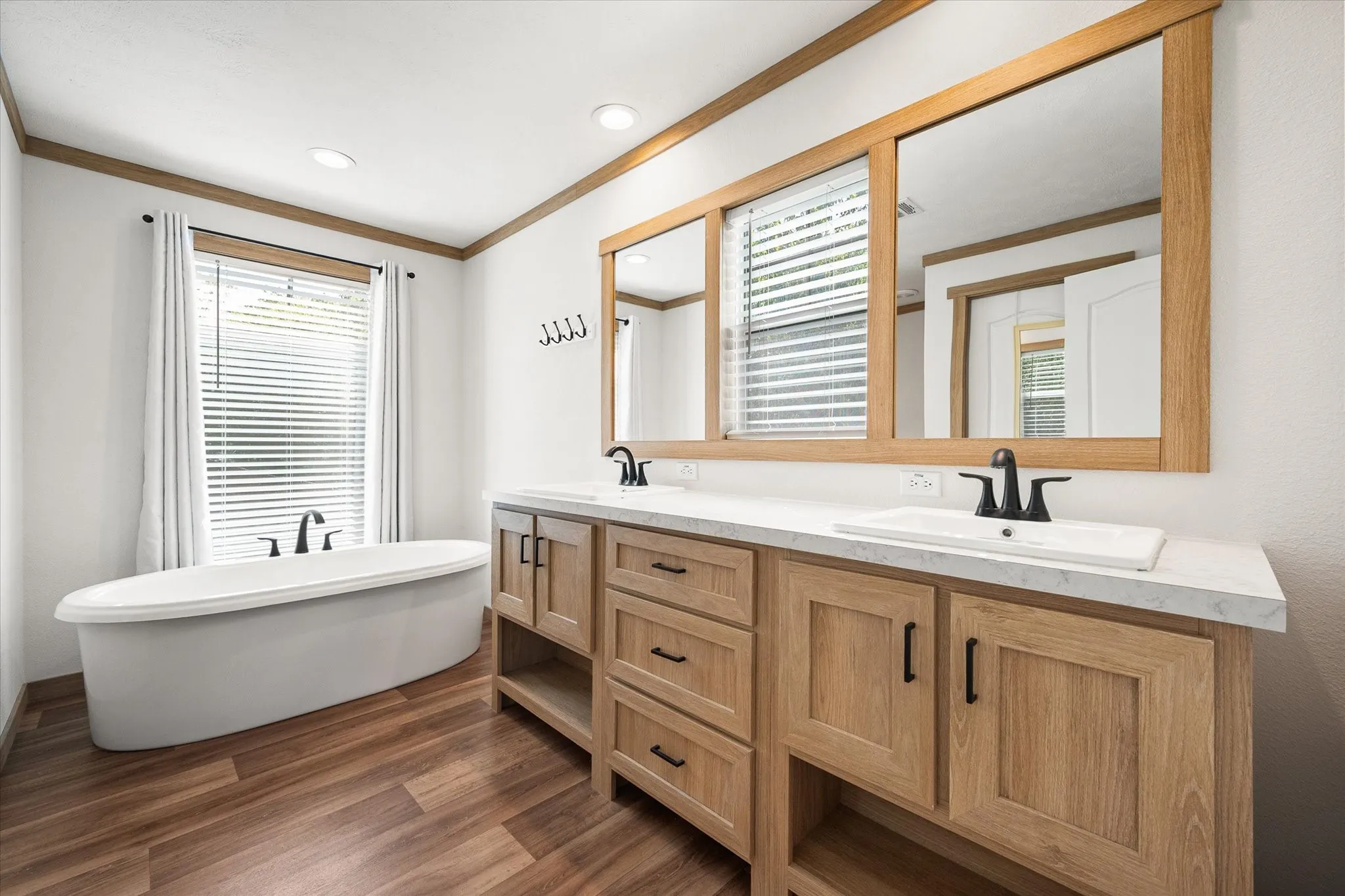 Primary bathroom showcases dual sinks, generous vanity storage, oversized mirror and a freestanding garden tub.