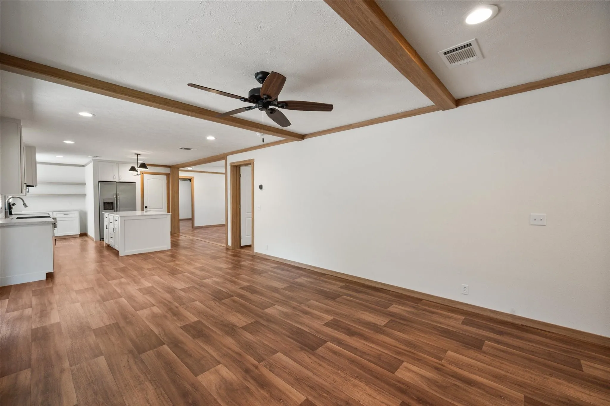 Open interior layout provides flexible living/dining space with wood-look laminate flooring, recessed lighting and easy access to the kitchen
