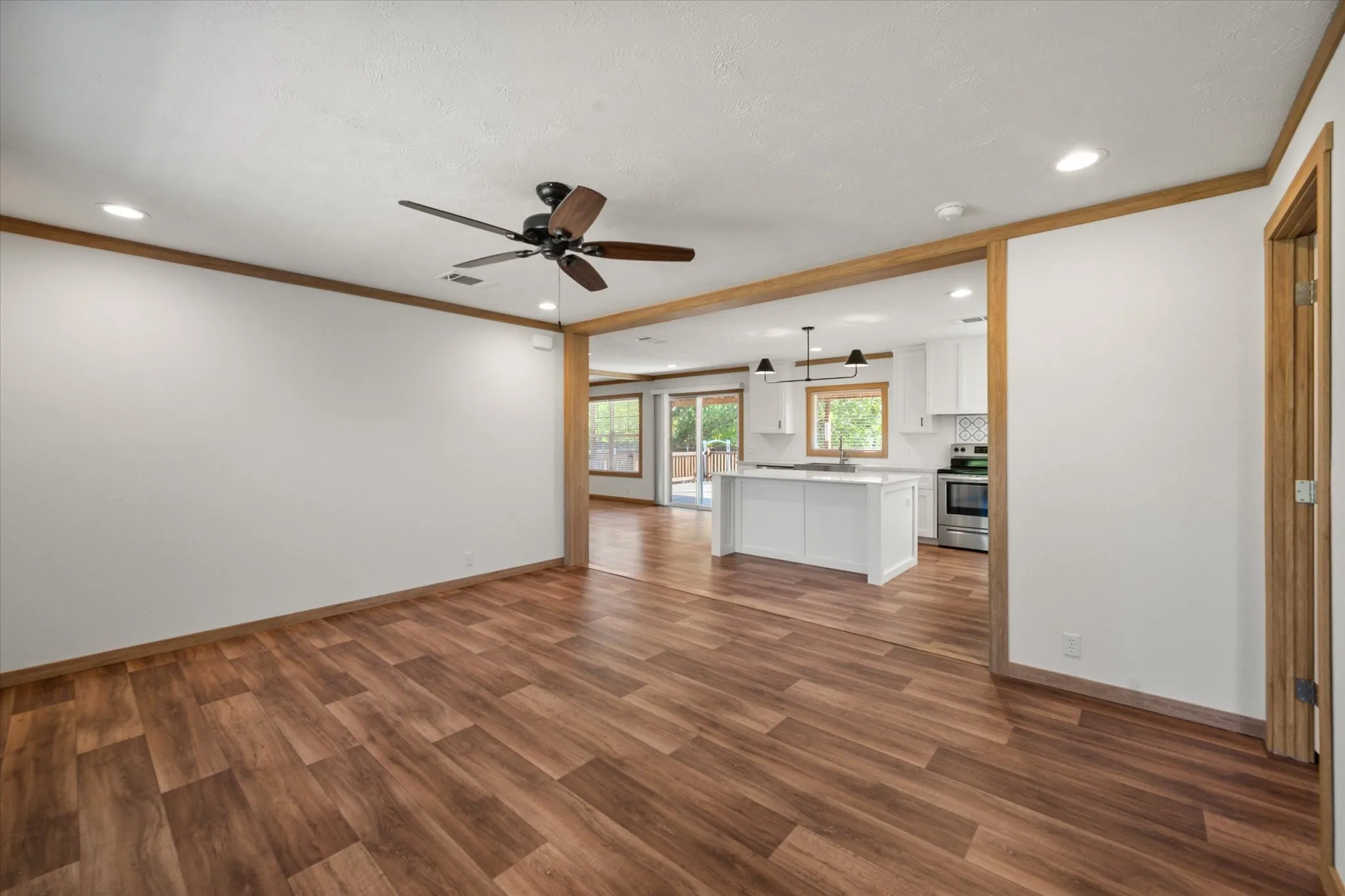 Bright open-concept living area at this Kerens TX home with wood-look flooring, recessed lighting and easy access to the kitchen.