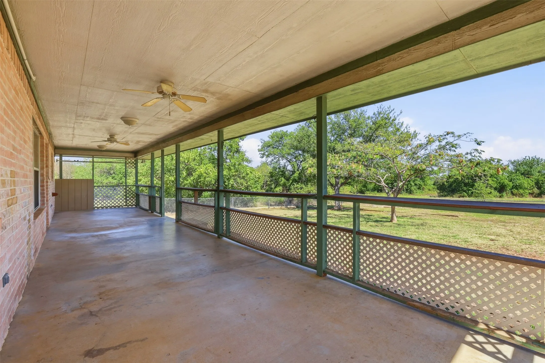 Expansive screened porch with concrete flooring and multiple ceiling fans