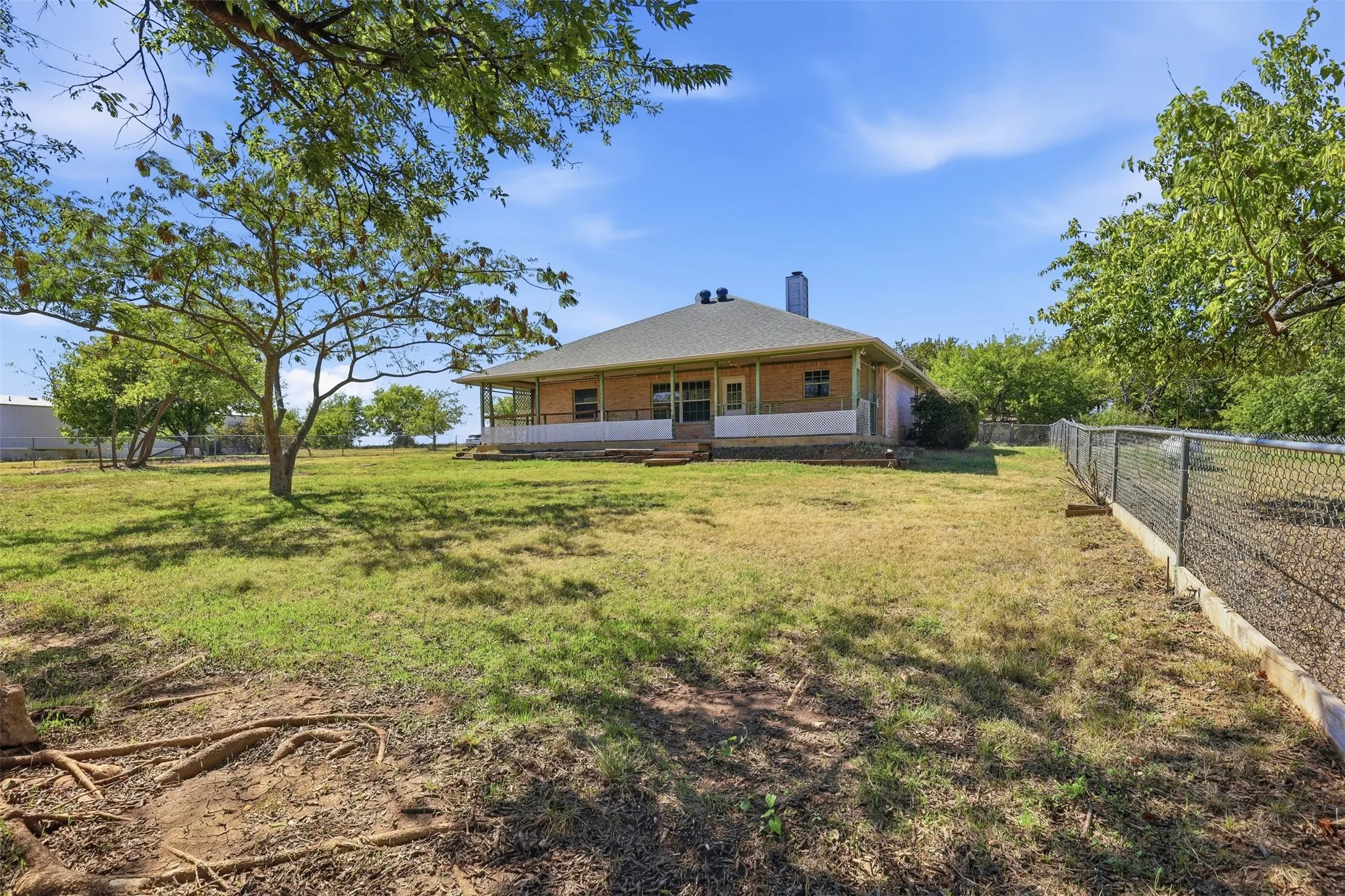 Expansive property featuring mature trees and a chain-link fence