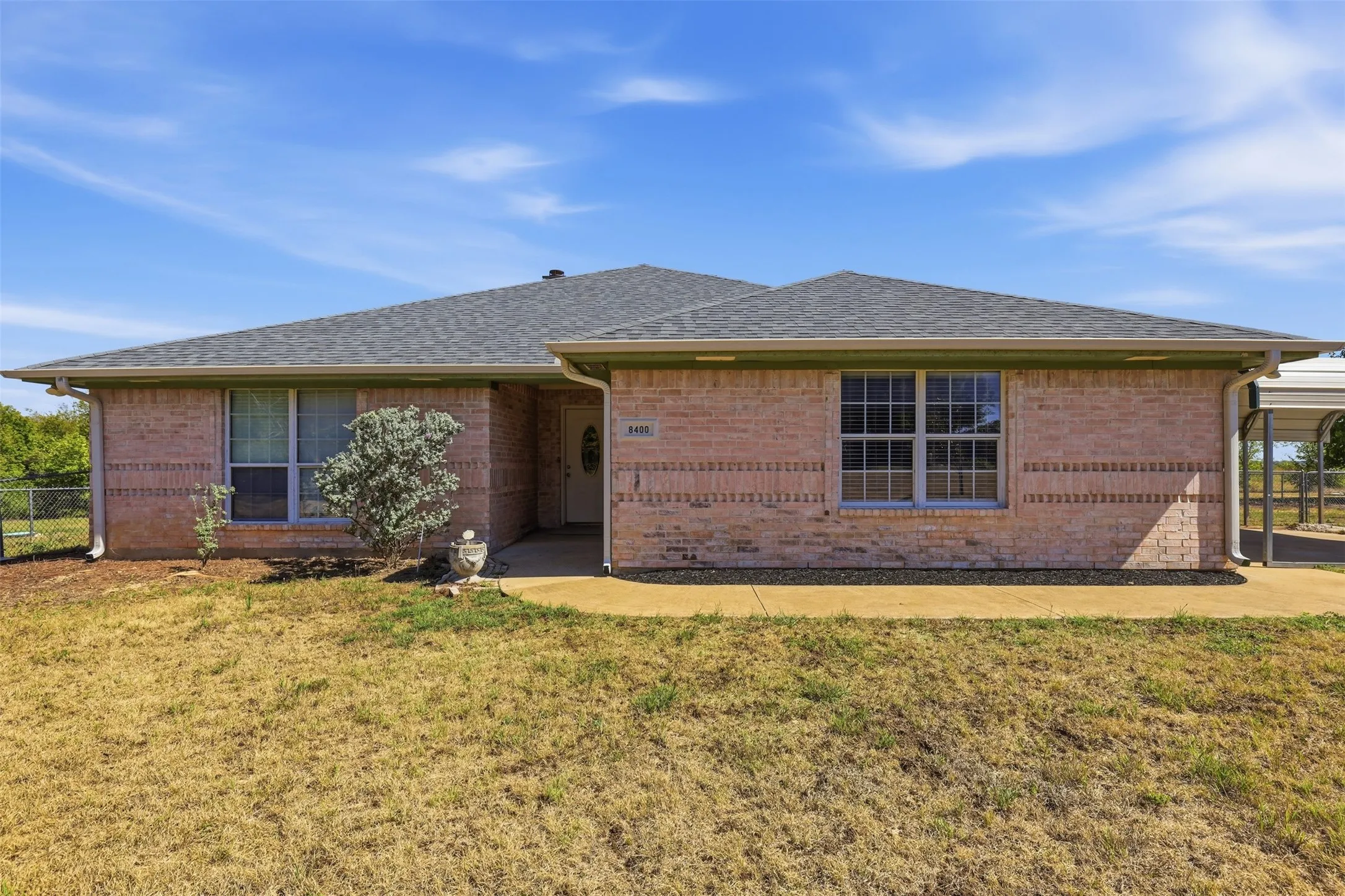 Brick exterior with a gabled roof, attached carport, and a concrete walkway