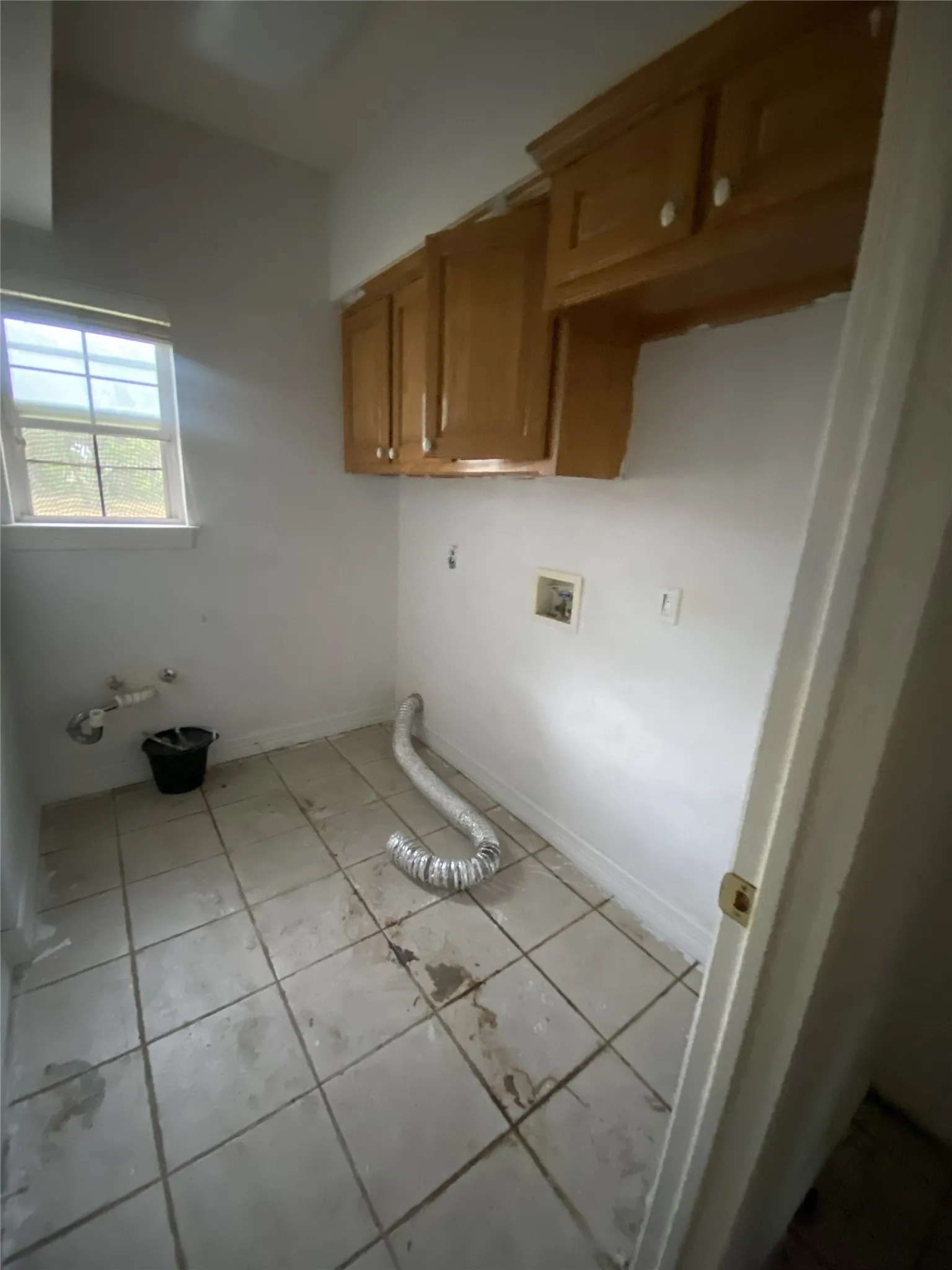 Wood-finish cabinetry, tile flooring, and a single window