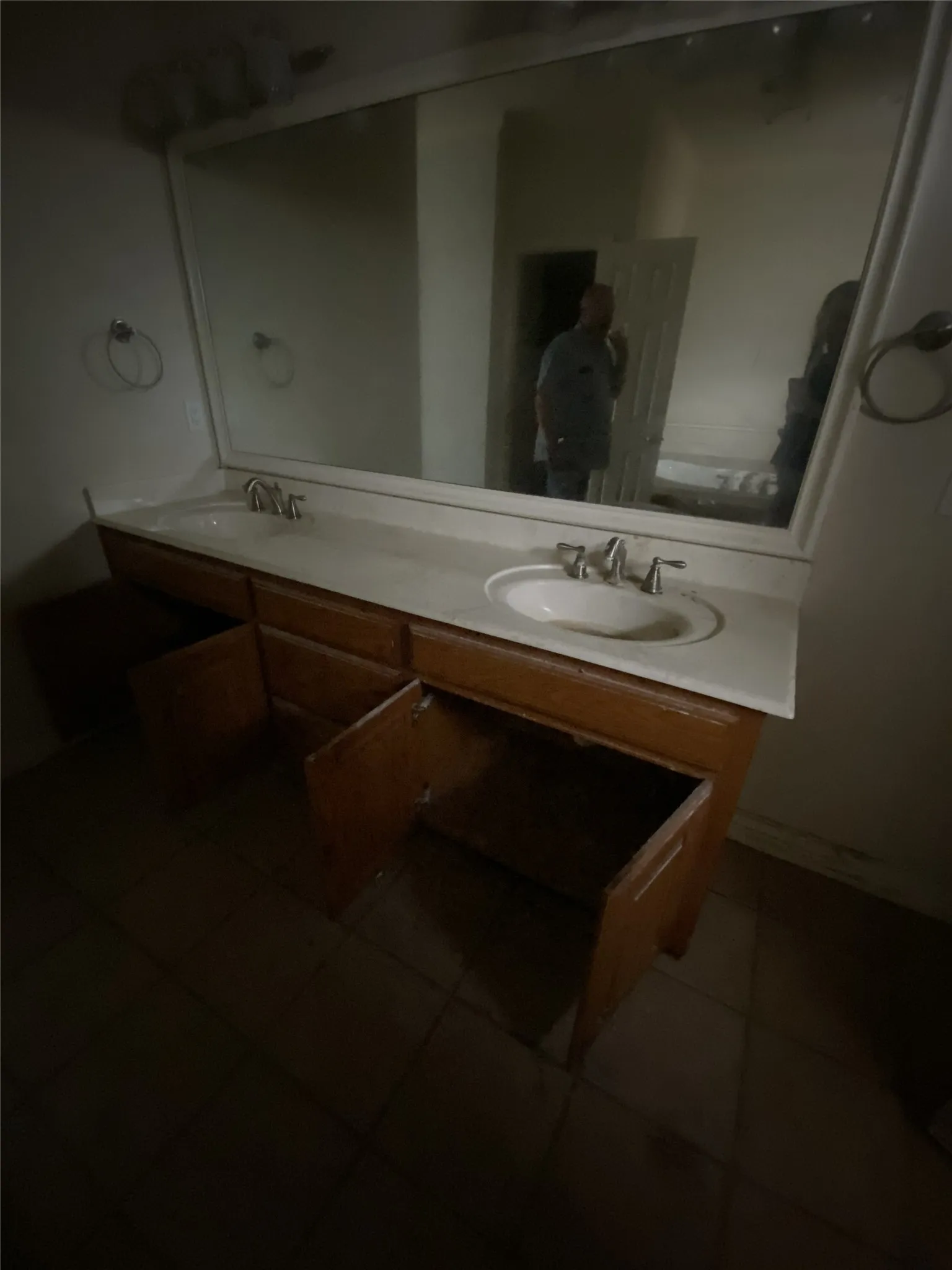 Dual vanity with integrated sinks, a large wall-mounted mirror, and tile flooring