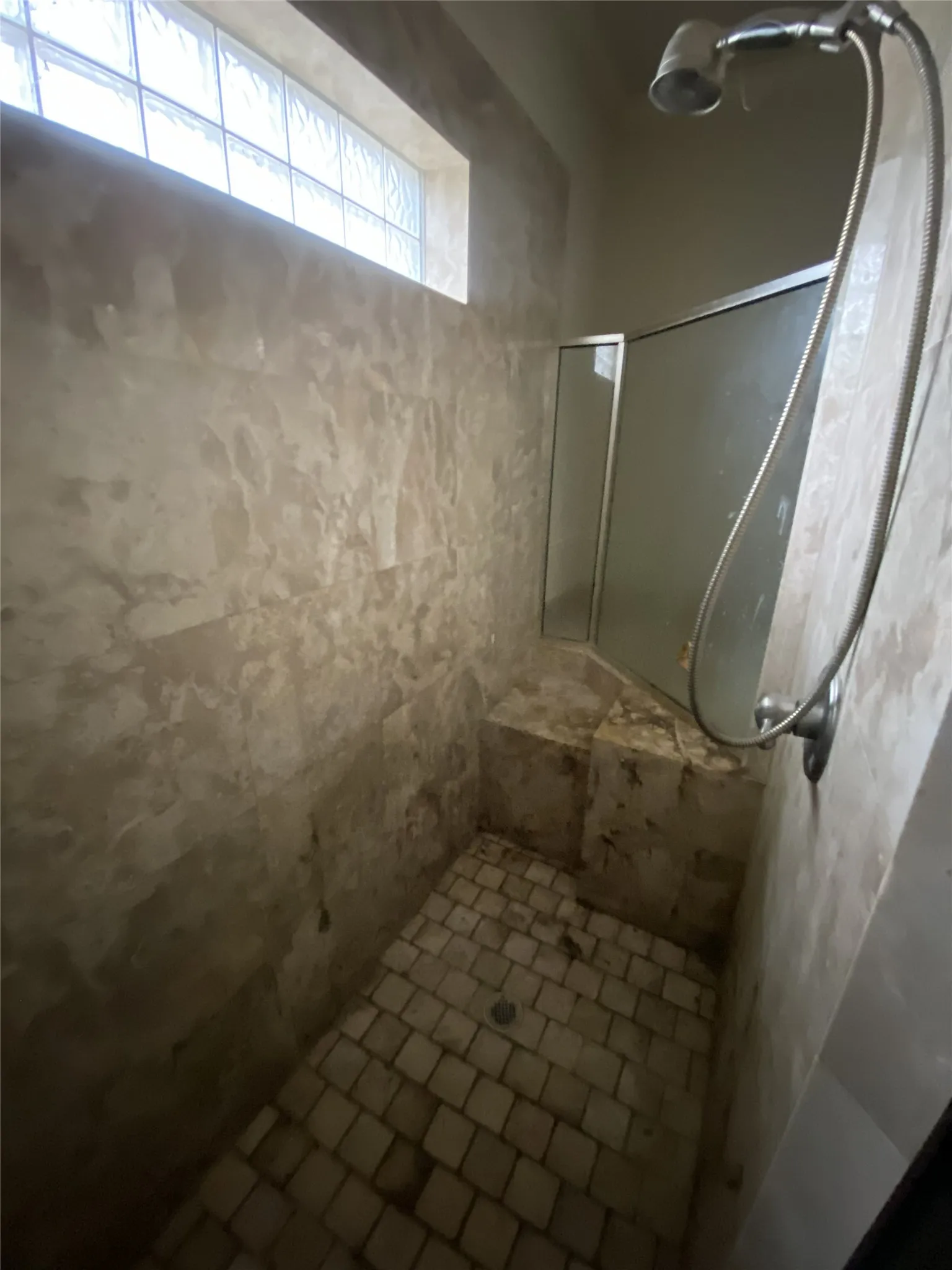 Tiled shower enclosure with a glass block window and a built-in shower bench