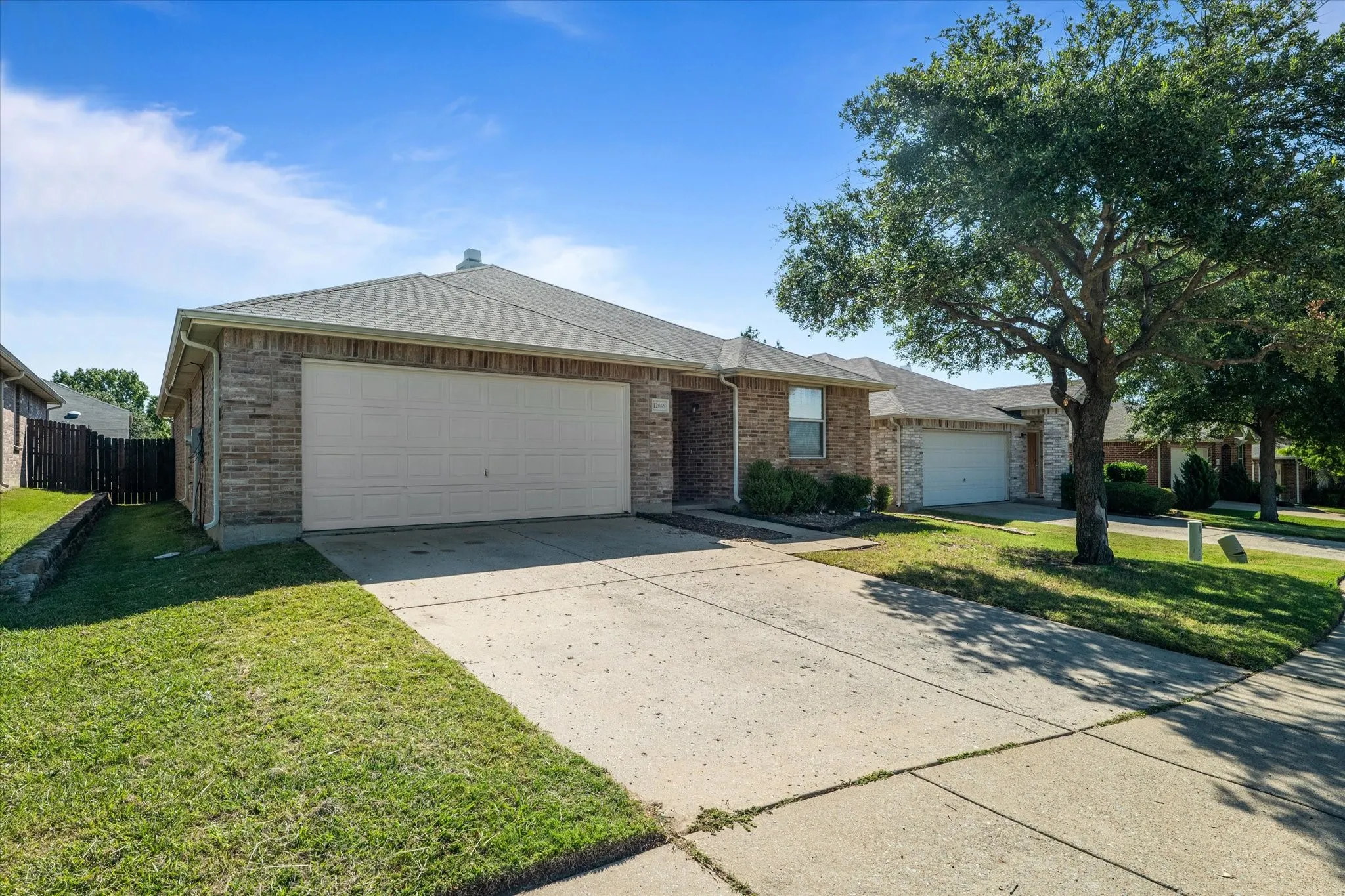 Single story home with an attached garage, concrete driveway, a shingled roof, and brick siding