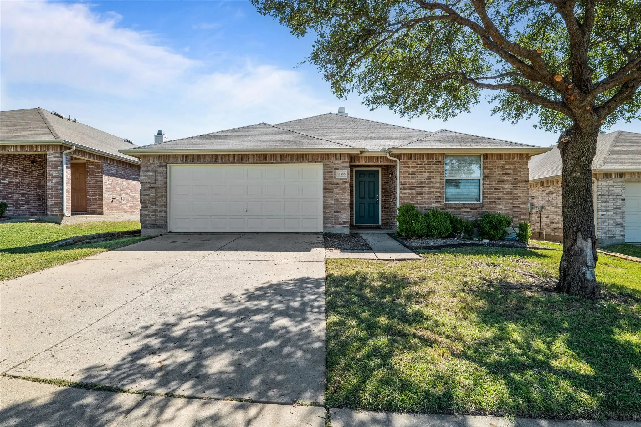 Ranch-style home with driveway, a garage, roof with shingles, a front yard, and brick siding