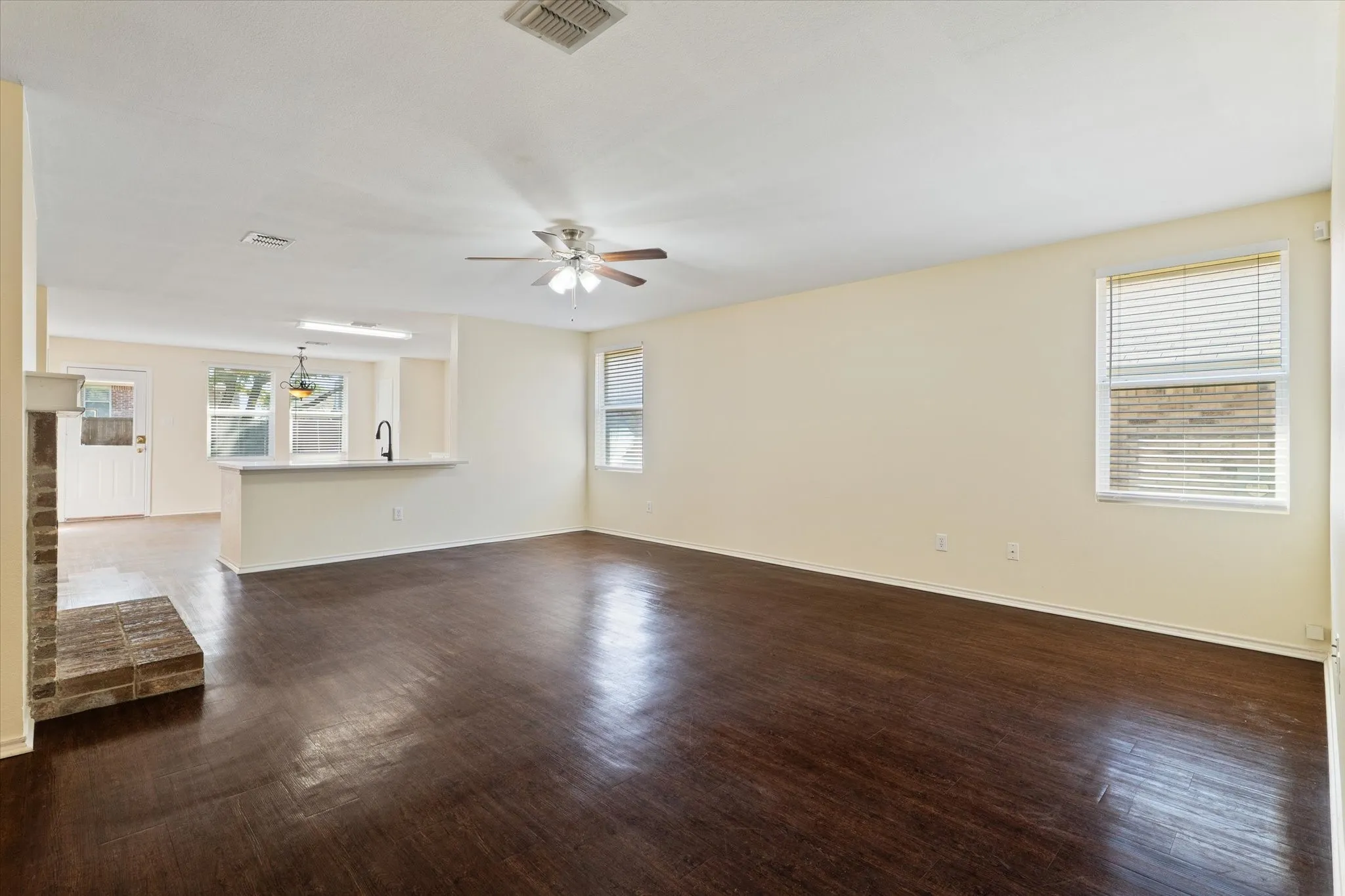 Unfurnished living room featuring ceiling fan and dark wood-style flooring