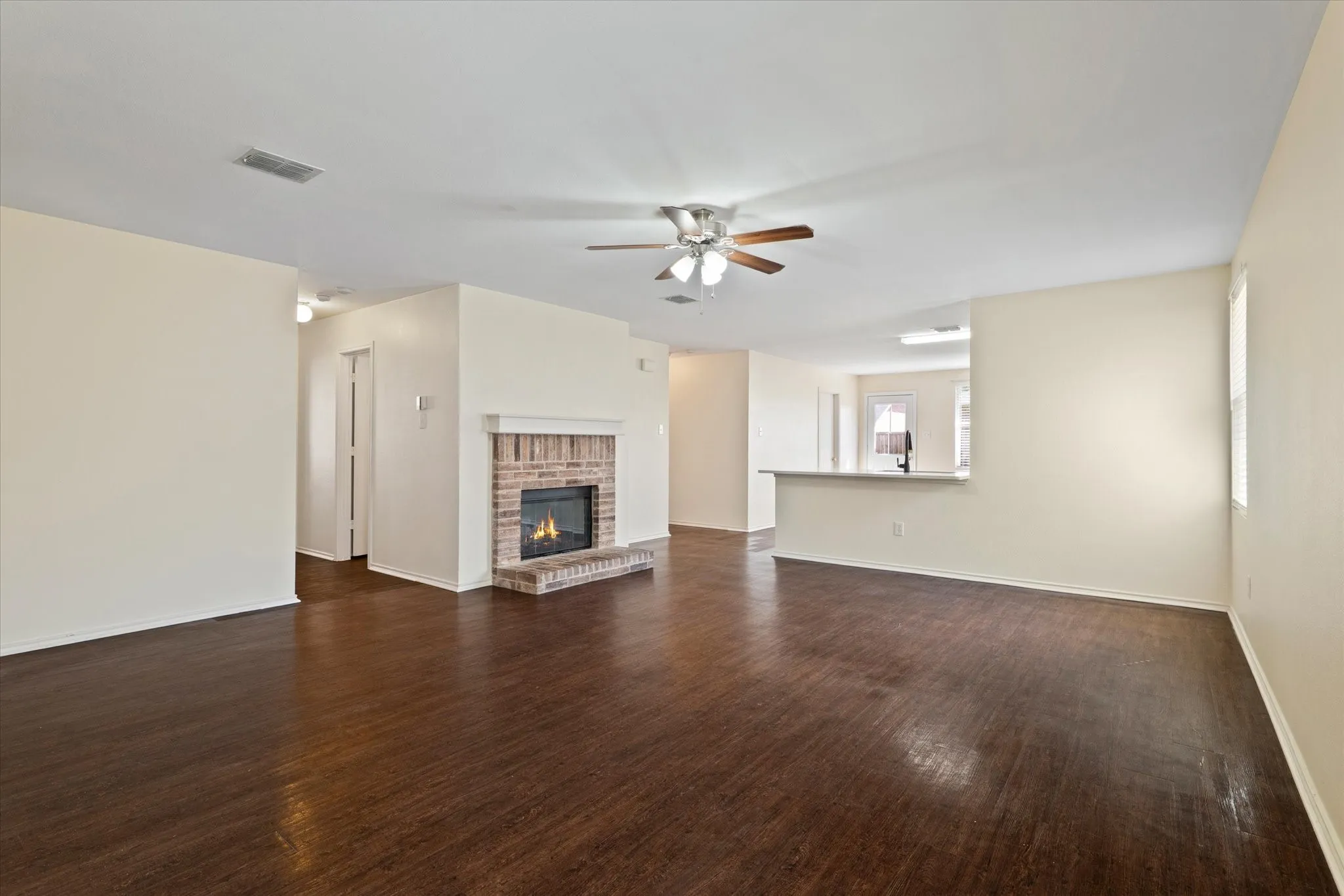 Unfurnished living room featuring a ceiling fan, dark wood finished floors, and a fireplace