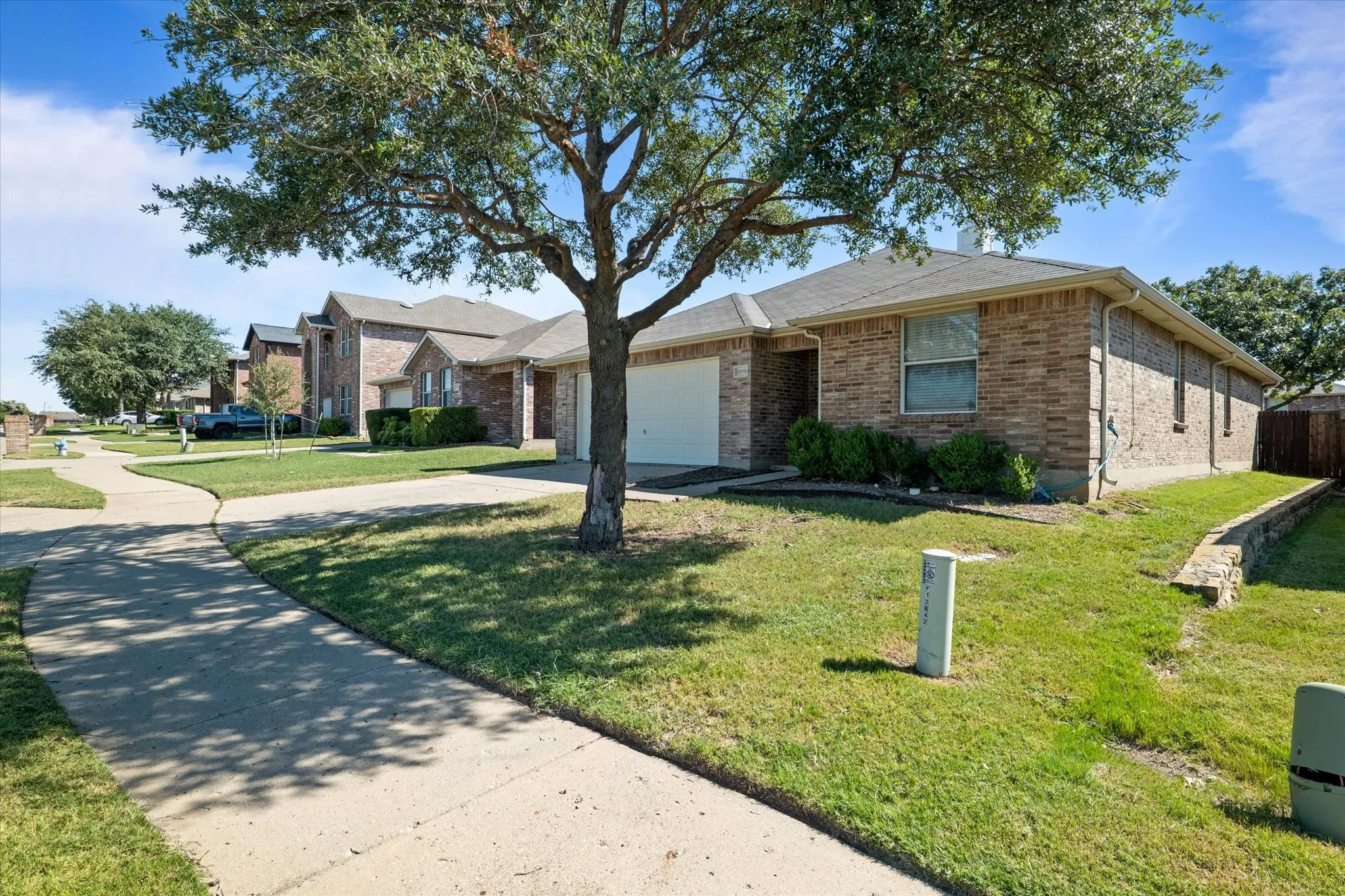 Single story home featuring driveway, an attached garage, brick siding, and a residential view
