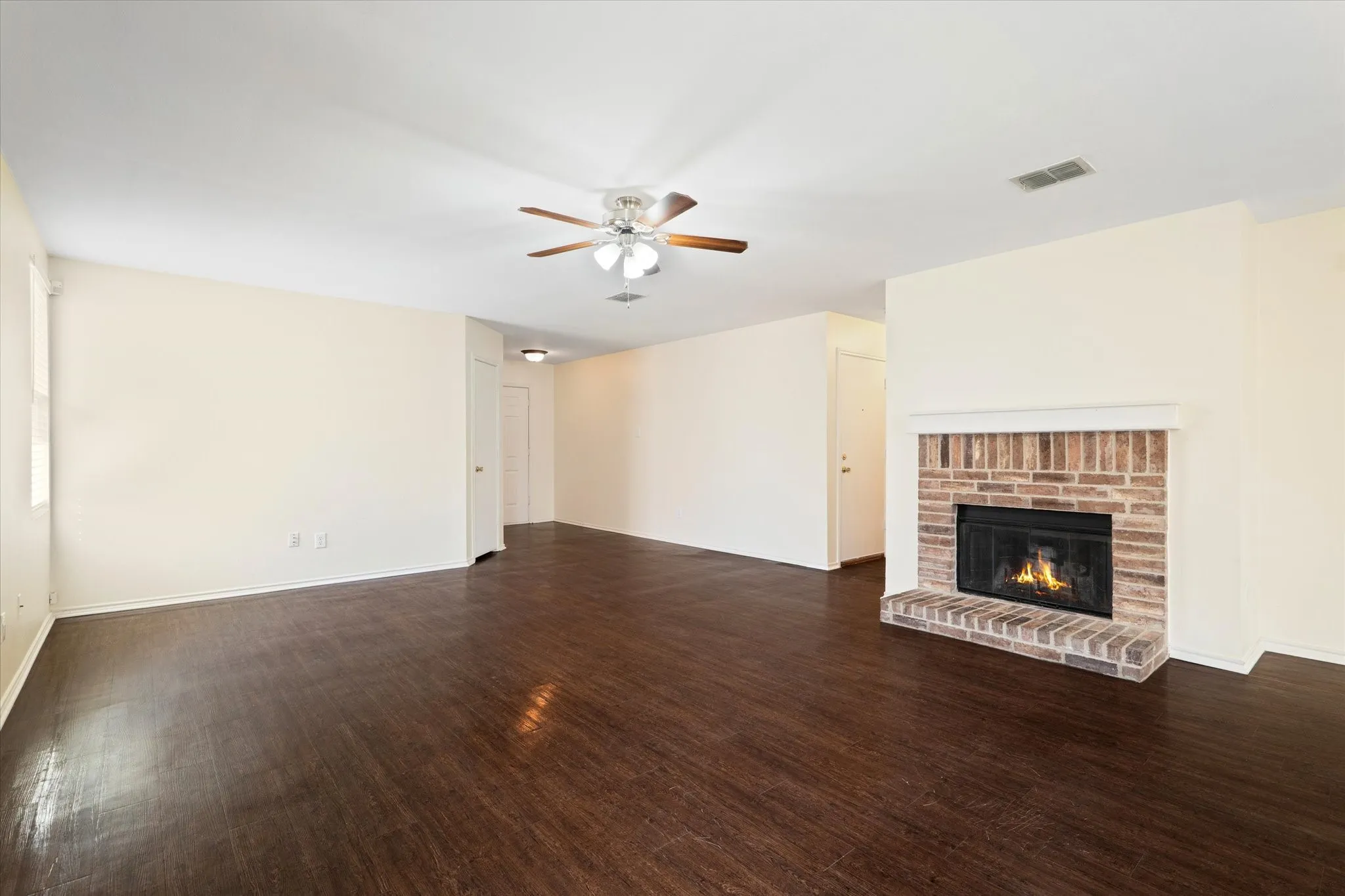 Unfurnished living room with a ceiling fan, wood finished floors, and a fireplace