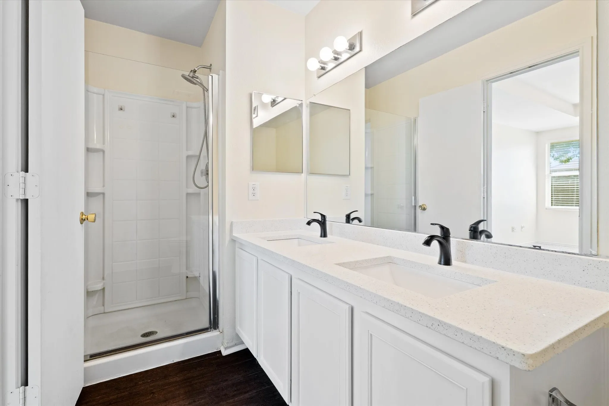 Full bath featuring double vanity, wood finished floors, and a shower