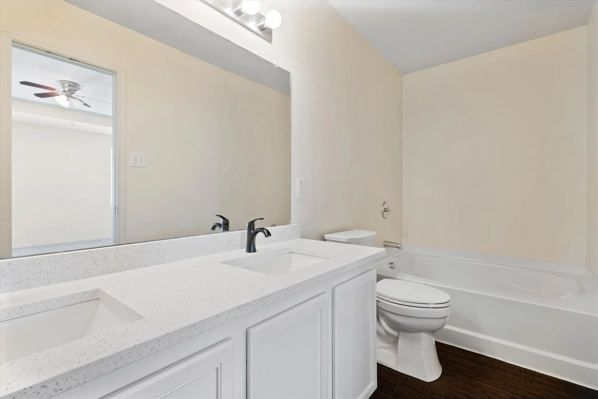 Full bath with wood finished floors, double vanity, a tub to relax in, and a ceiling fan