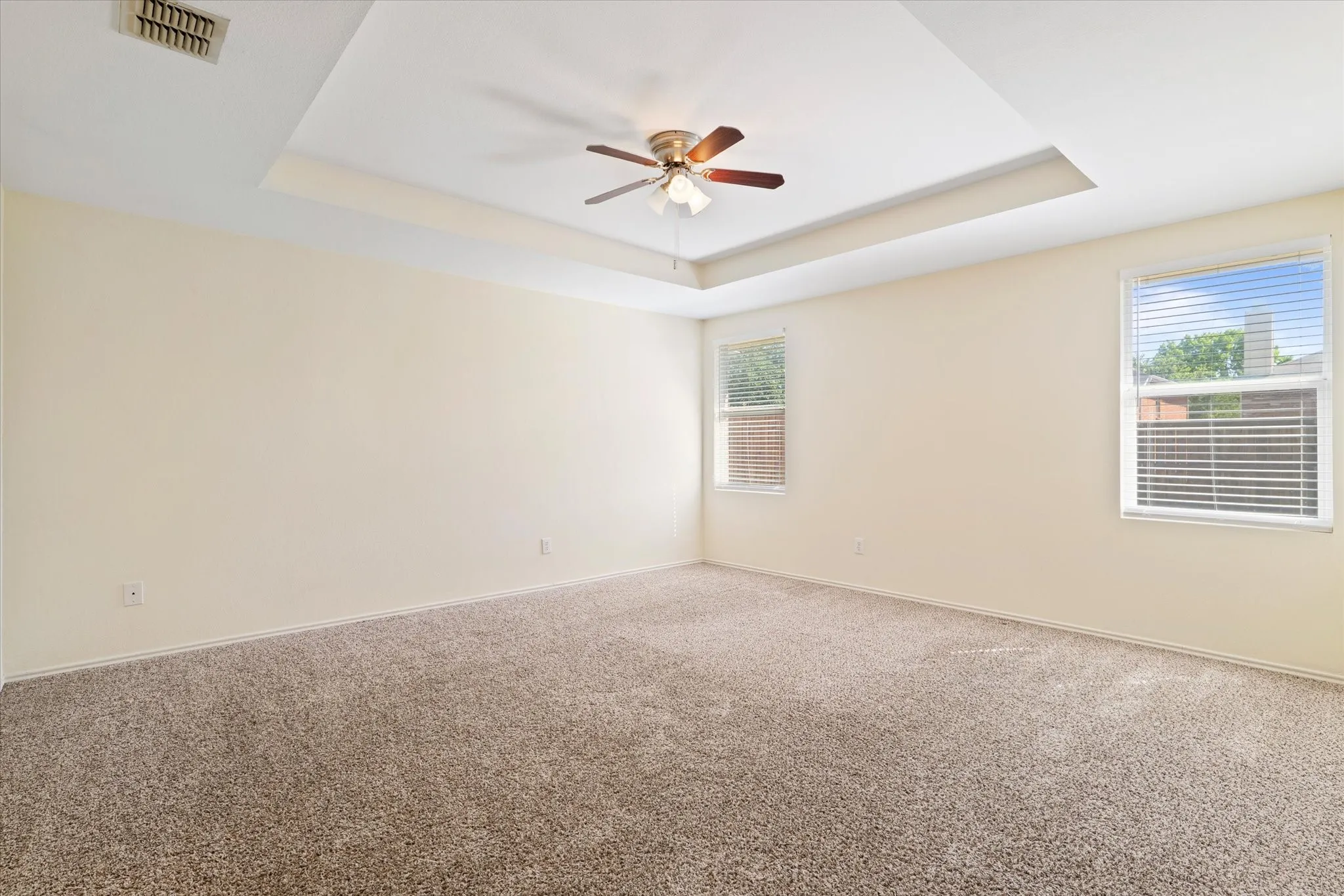 Unfurnished room with a tray ceiling, a ceiling fan, and carpet