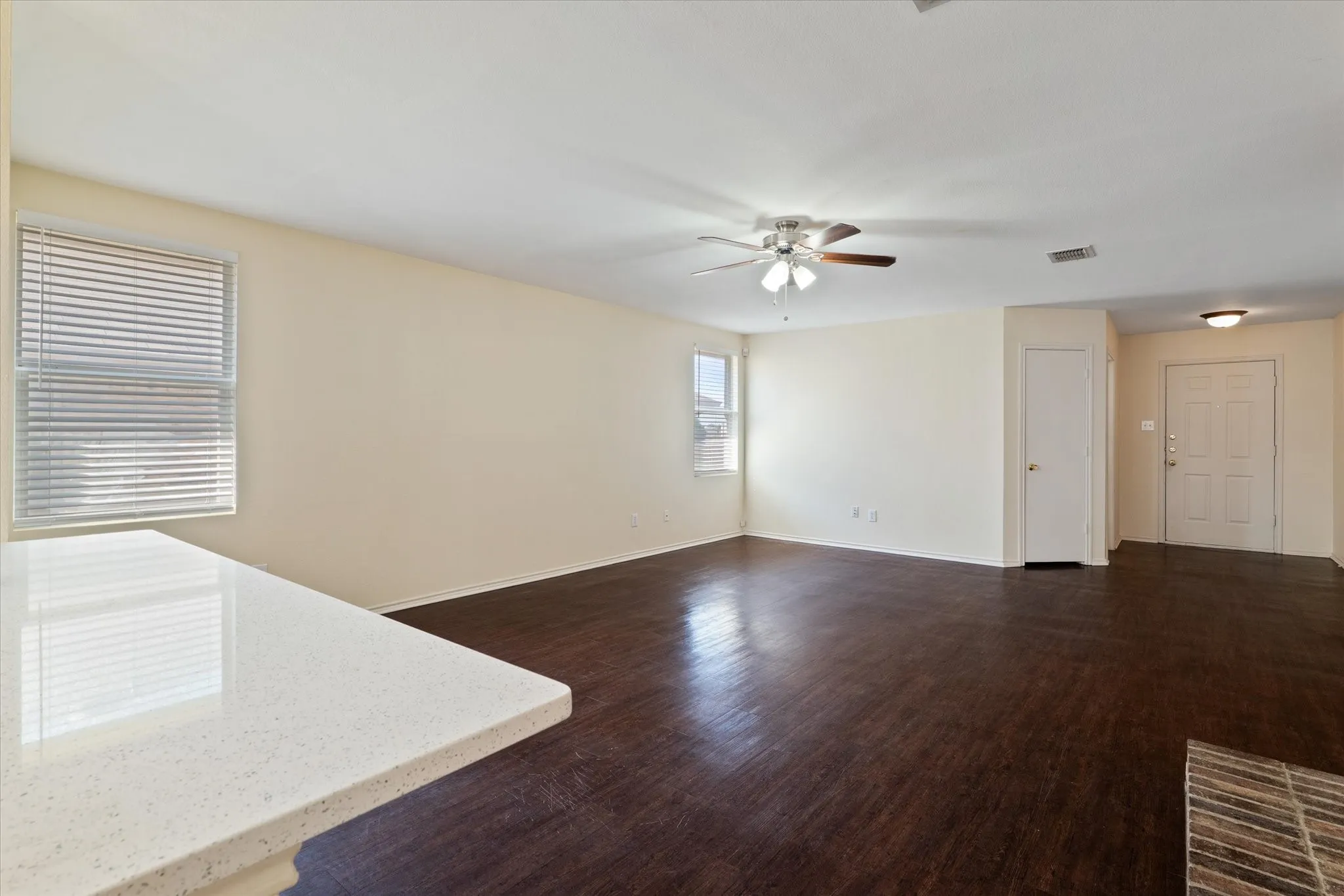 Unfurnished living room with ceiling fan and dark wood-style flooring