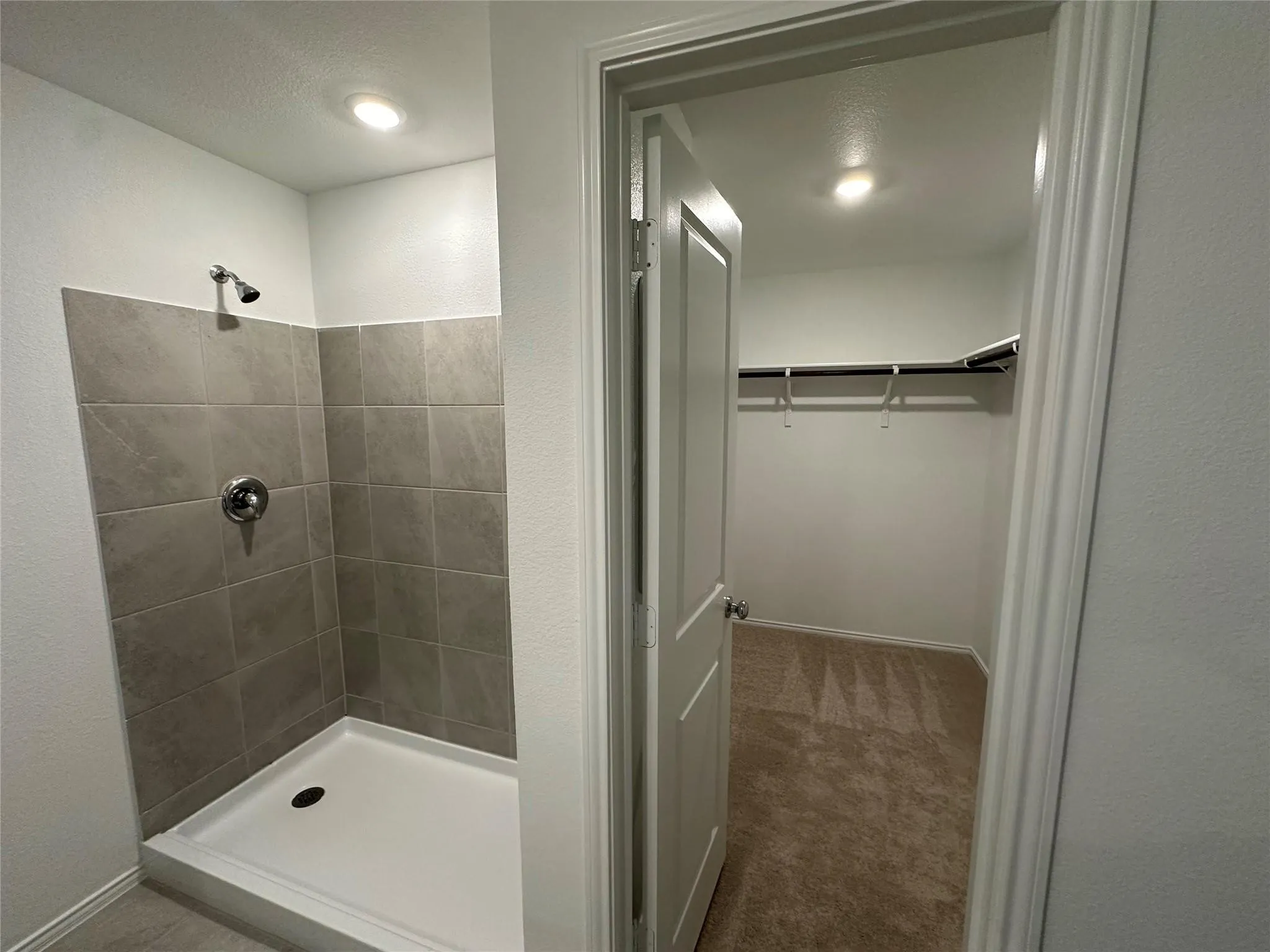 Walk-in shower with gray tile surround and chrome fixtures