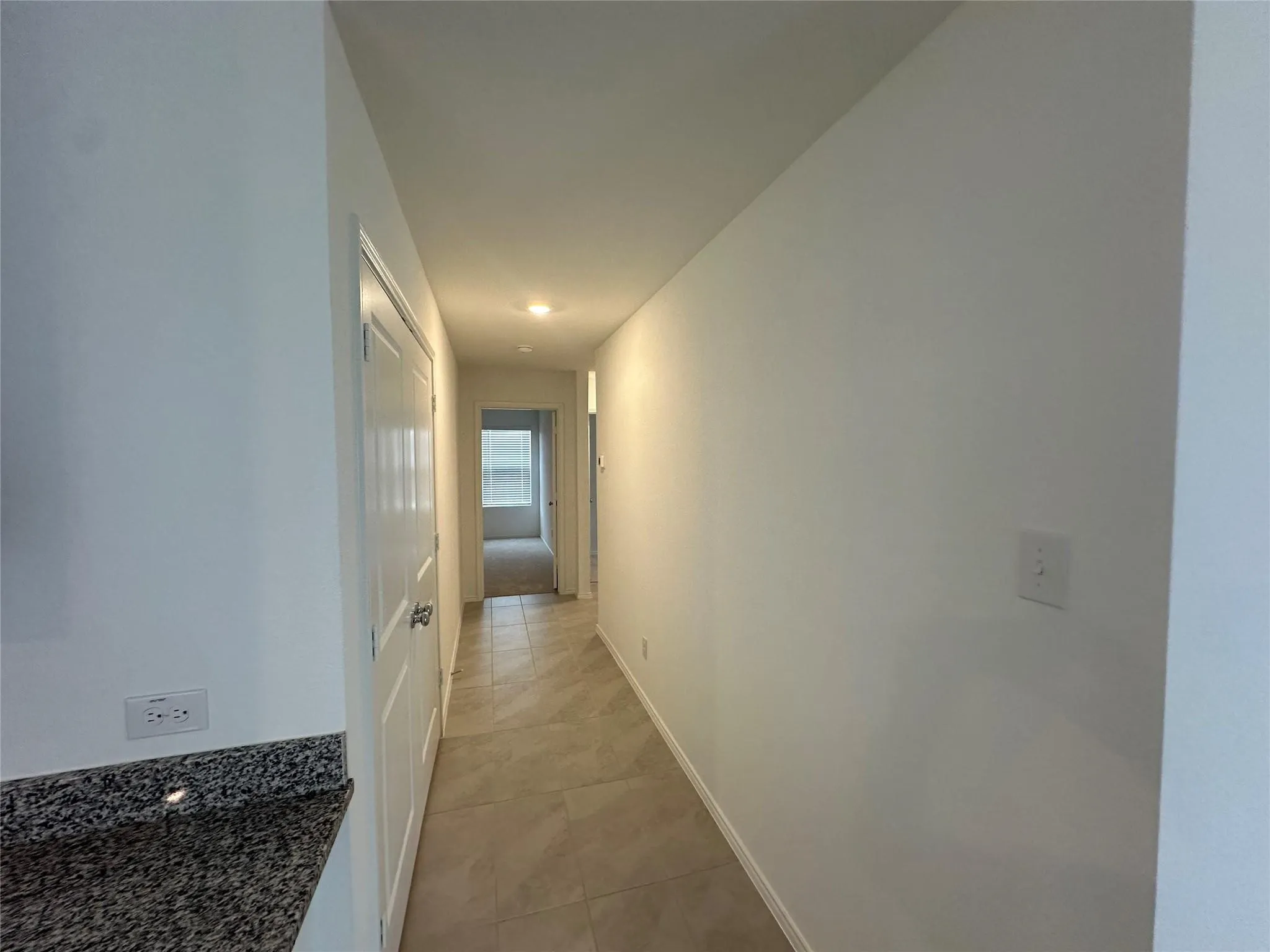 Hallway featuring neutral-toned tile flooring, recessed lighting, and white walls
