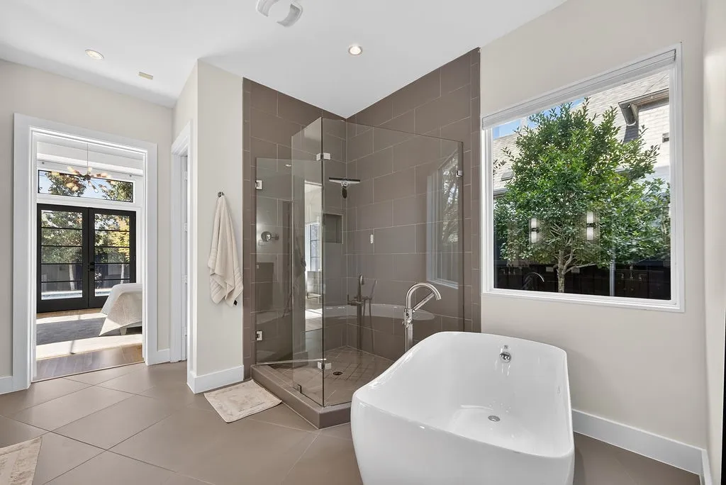 A free-standing soaking tub sits at the center of the primary bath, creating a dedicated spa-like routine at home
