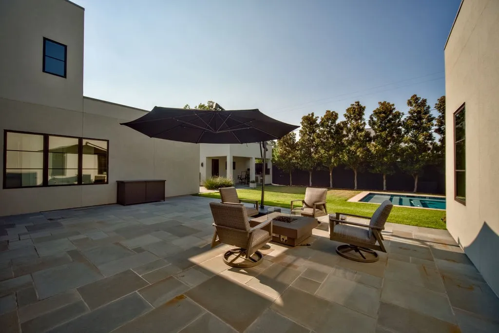 Positioned right off the main living area, this covered stone patio looks directly across the private yard, swimming pool, and integrated spa