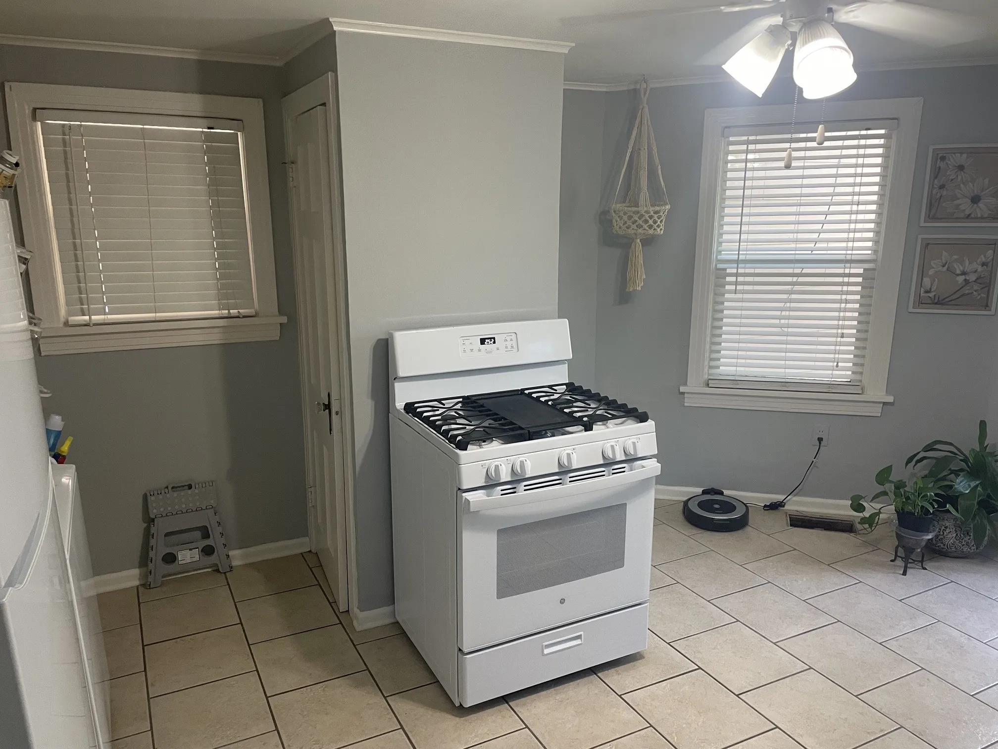 White gas range, ceiling fan with integrated lighting, tiled flooring, and multiple windows