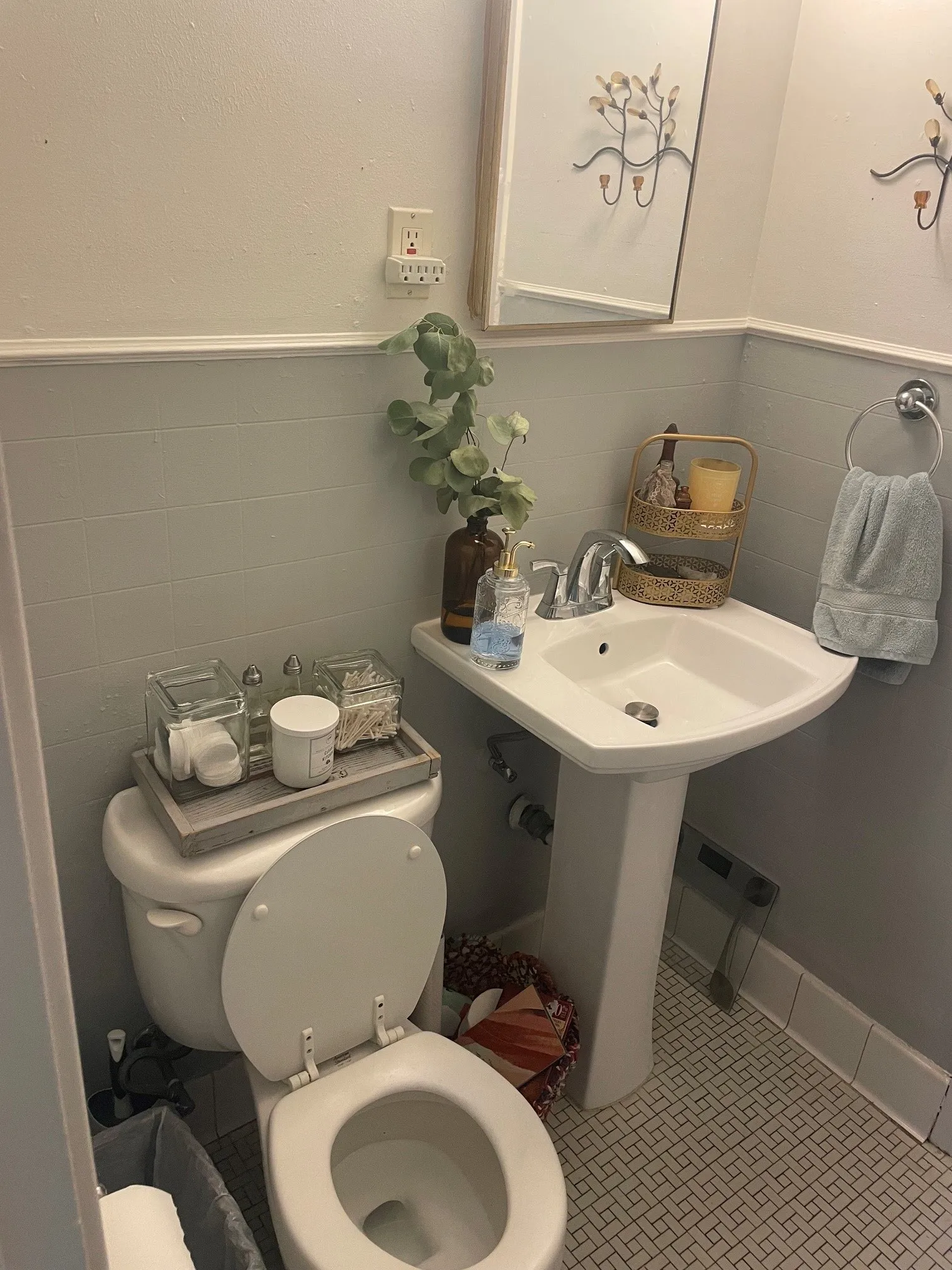 White pedestal sink with chrome faucet, white toilet, and patterned tile flooring