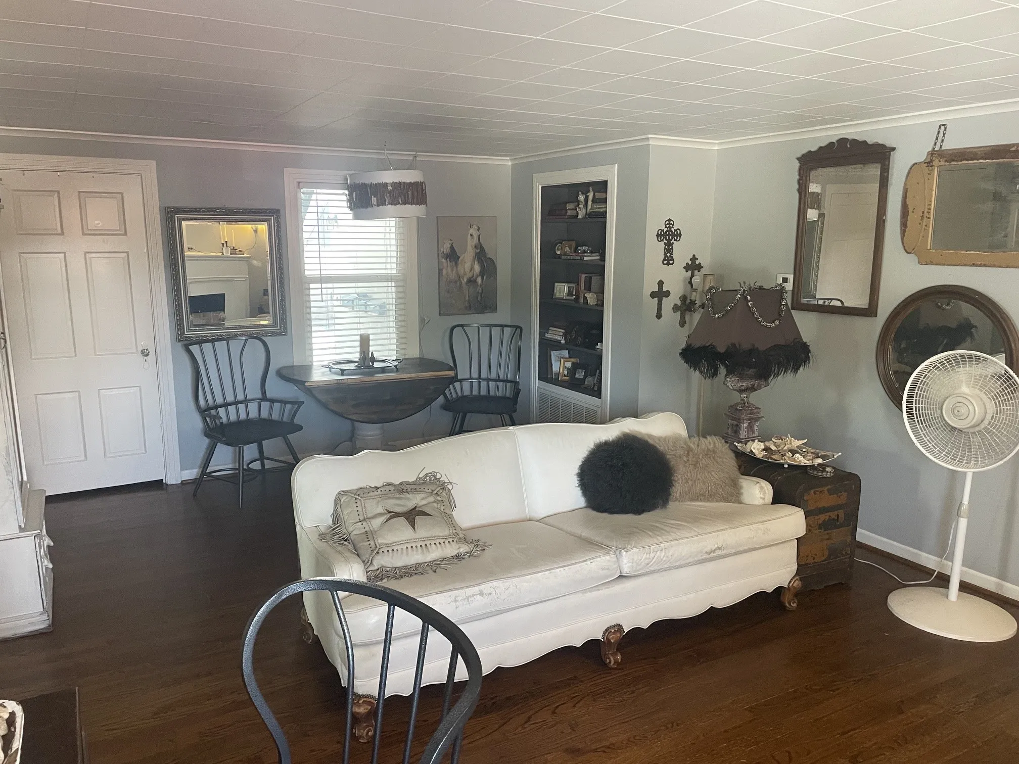 Wood-finish flooring, built-in shelving, white paneled door, and a window with blinds