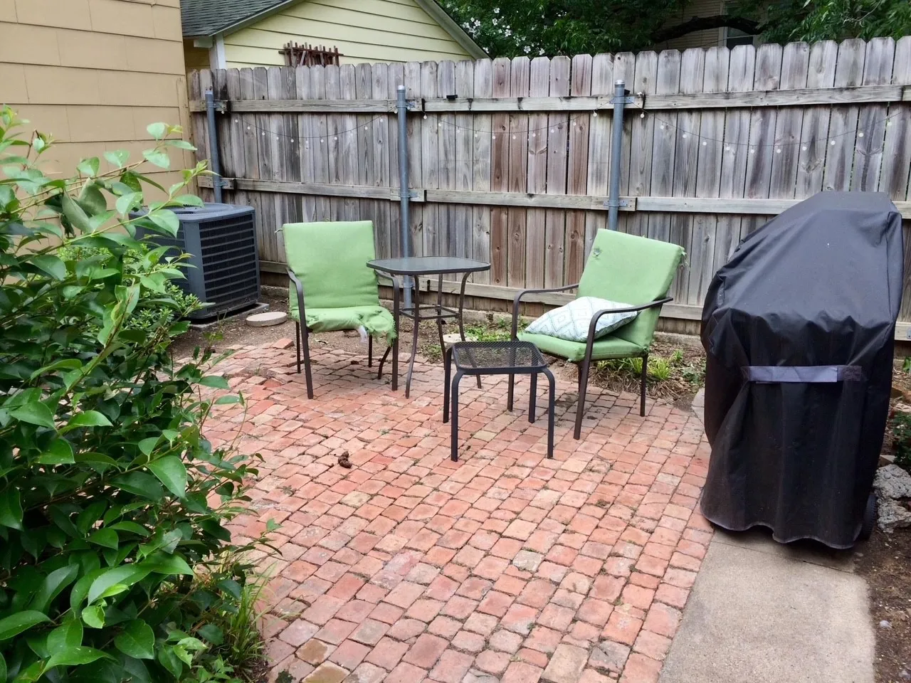 Brick paver patio with a wood privacy fence and established shrubbery